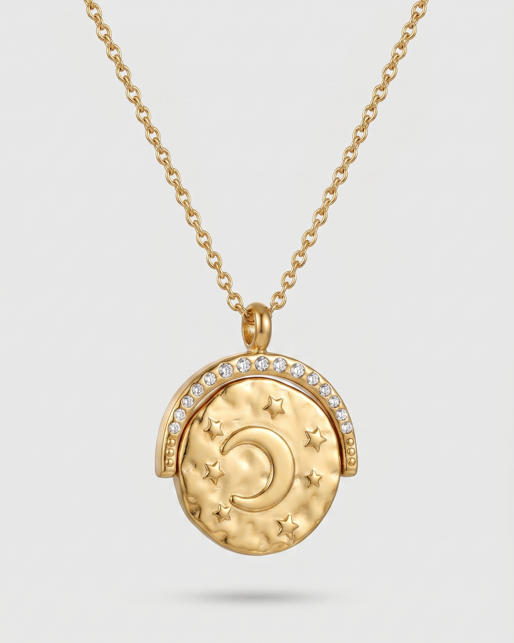 Gold necklace with a round pendant featuring celestial designs on a light gray background