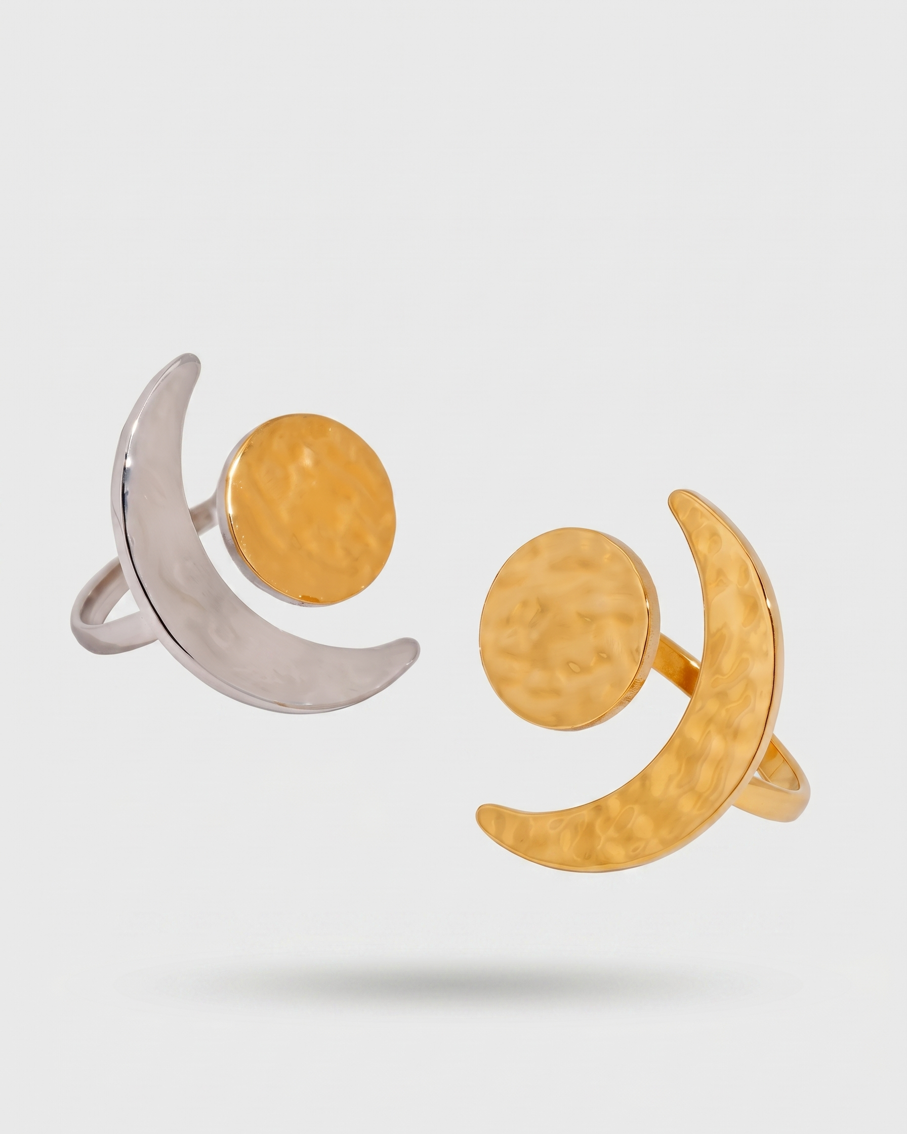 Two rings, one silver and one gold, on a light gray background