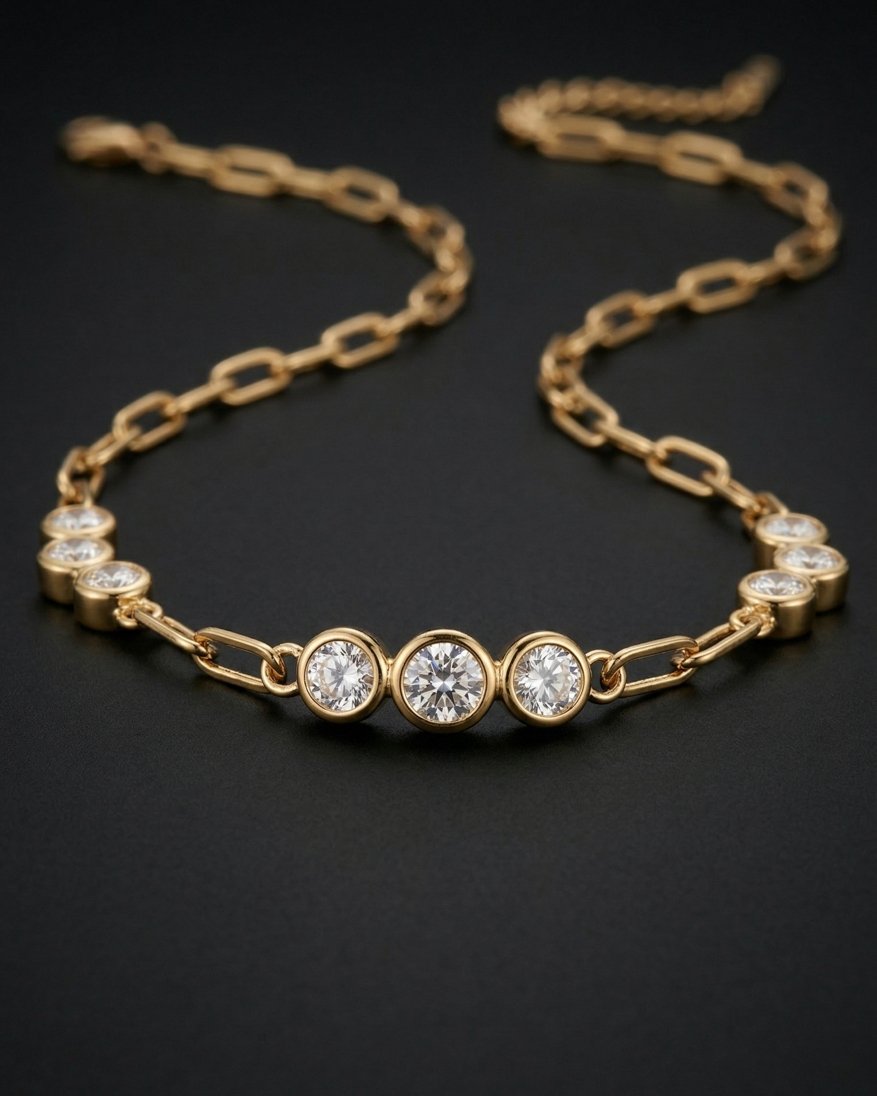 Gold necklace with three clear gemstones on a black background
