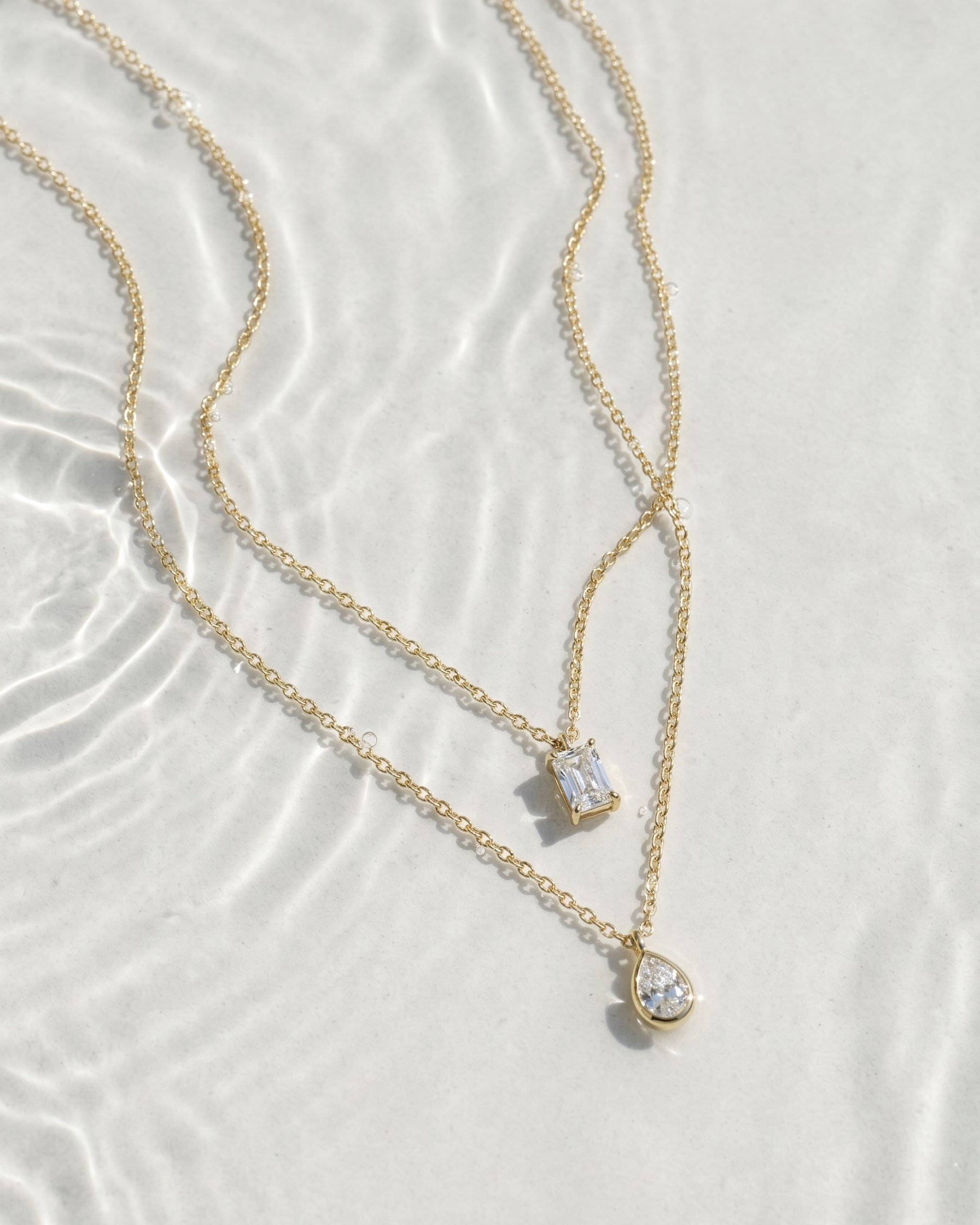 Gold necklace with heart-shaped pendants on a textured white surface