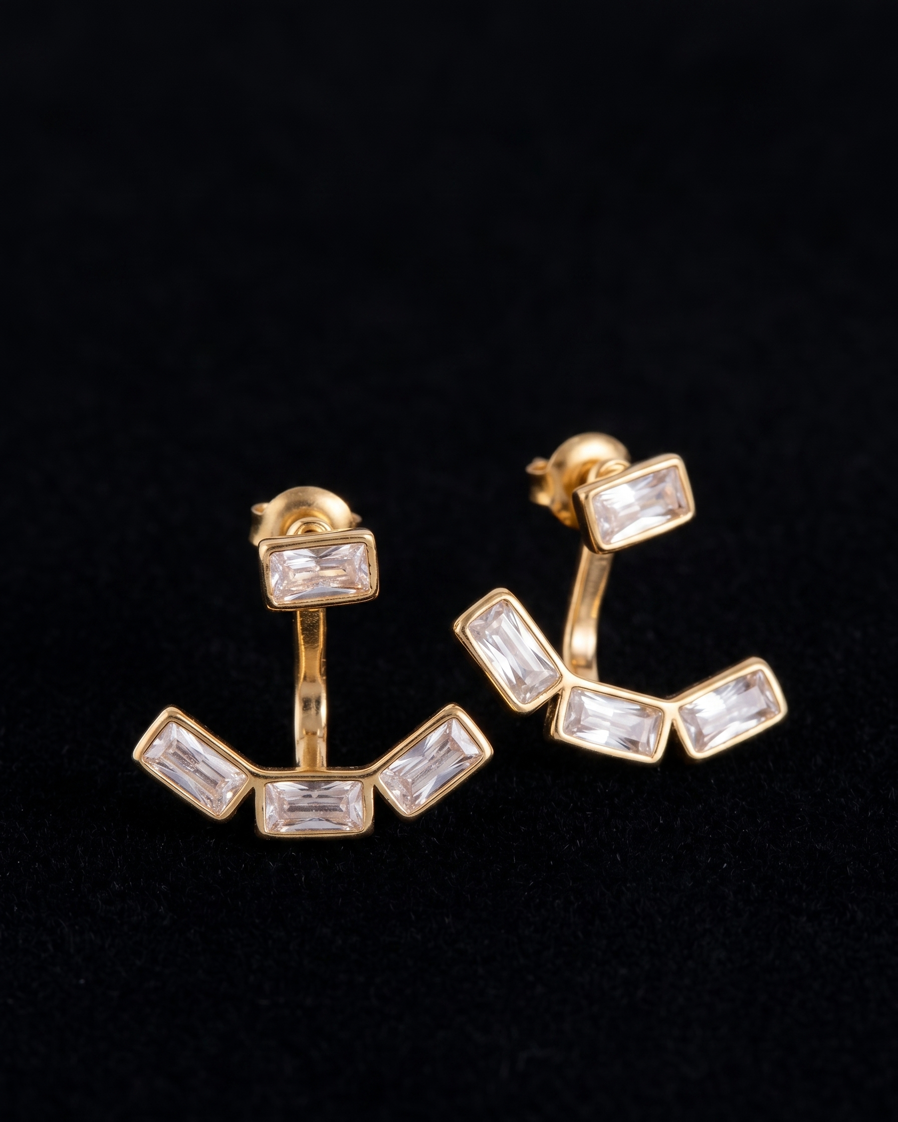 Gold earrings with clear gemstones on a black background