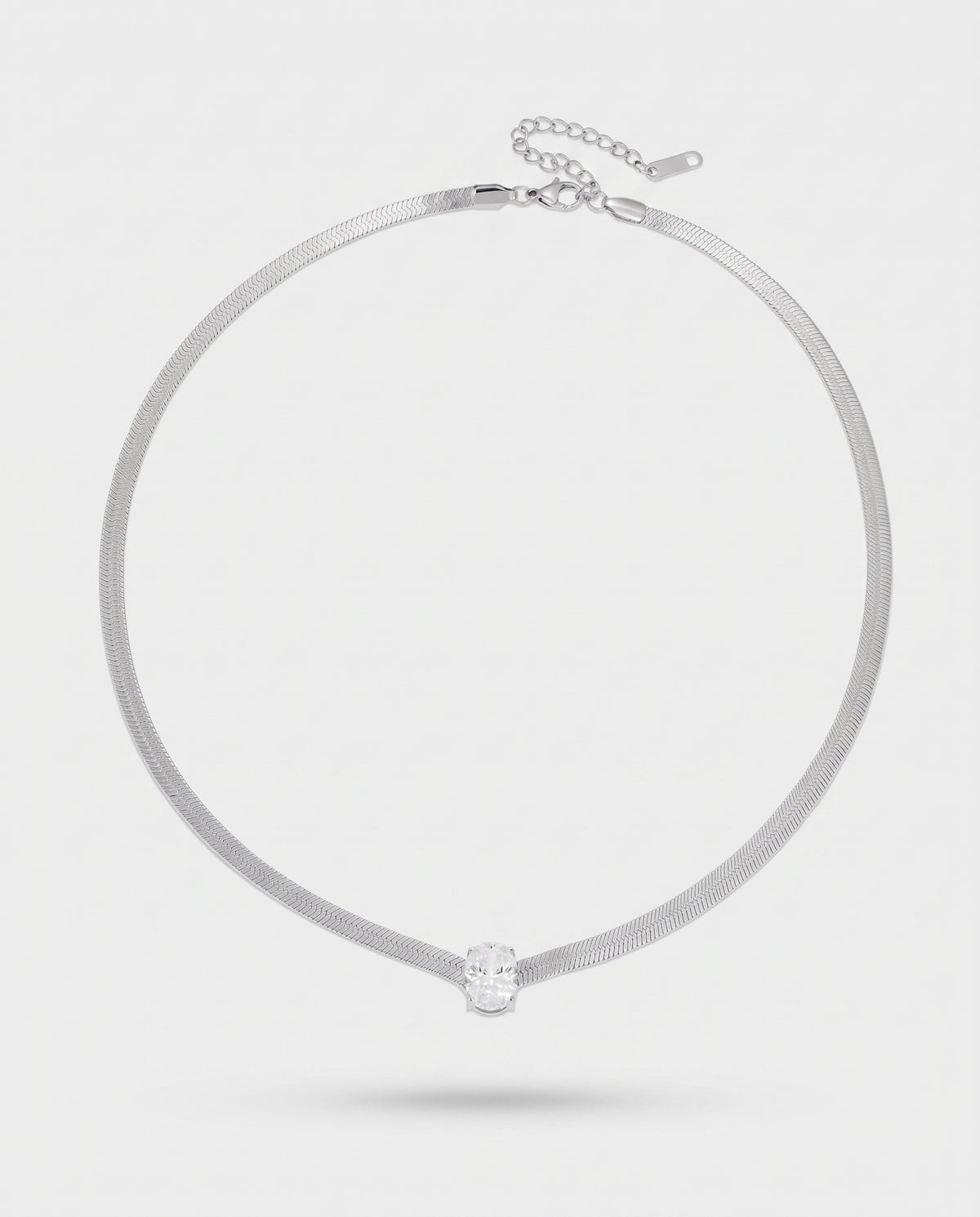 A silver-toned snake chain choker necklace with a single clear faceted gemstone pendant, displayed on a light gray background.