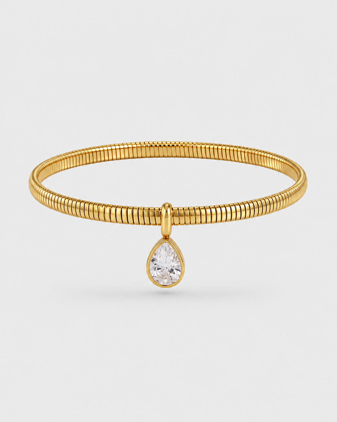 A gold-plated bangle bracelet with a textured, ribbed band and a dangling pear-cut clear gemstone charm, shown on a light gray background.