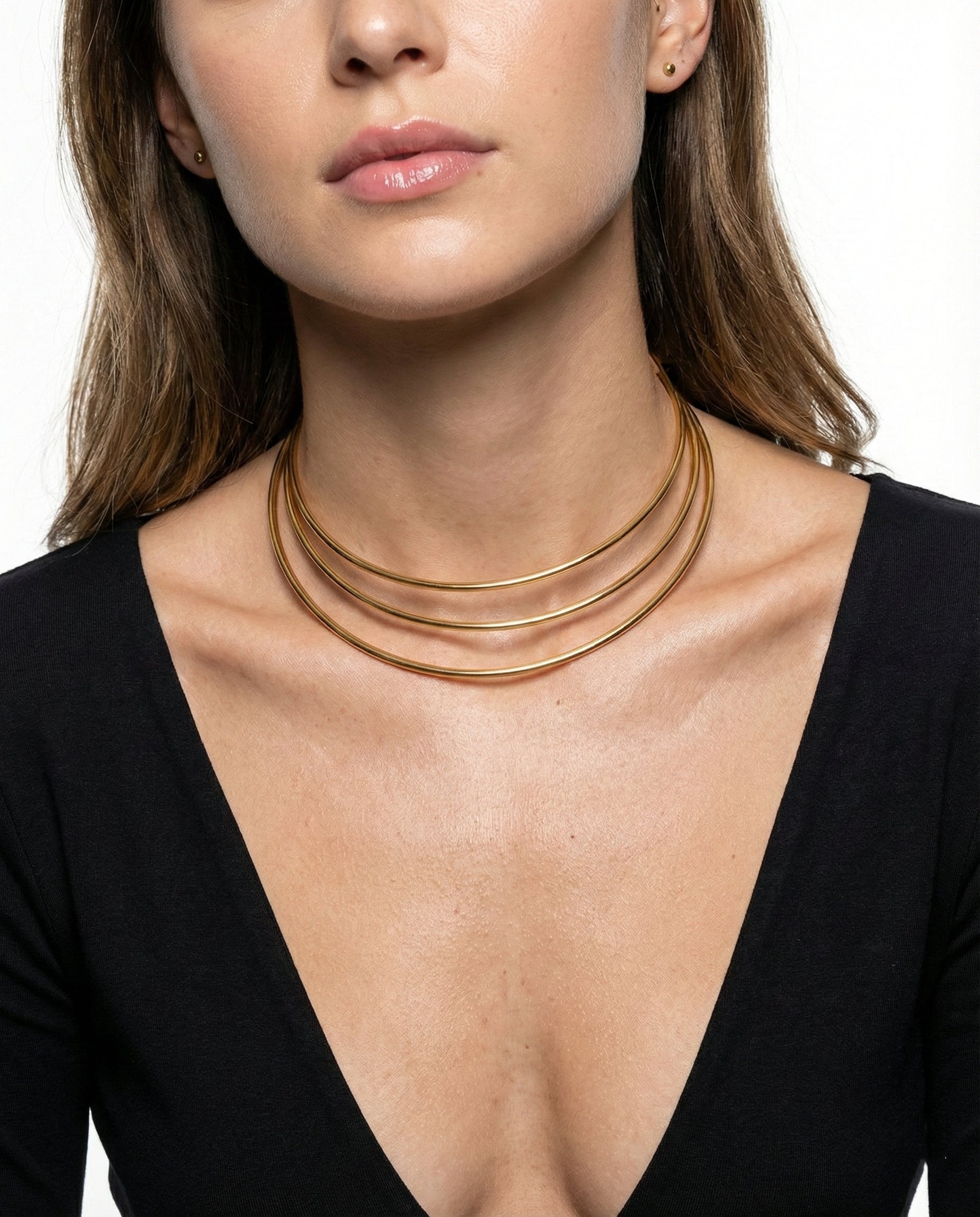 Woman wearing a gold necklace with a plain background
