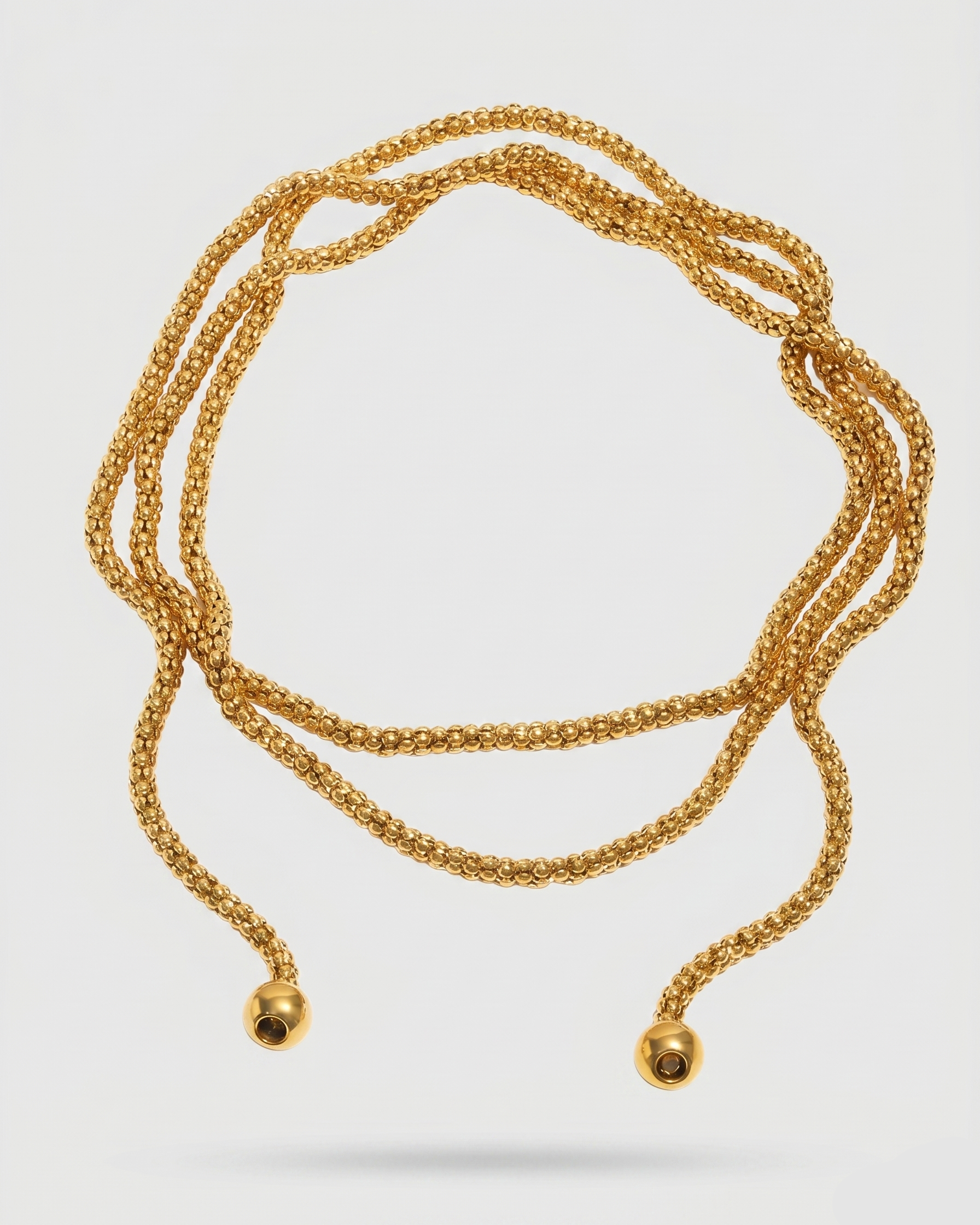 Gold necklace with spherical ends on a white background