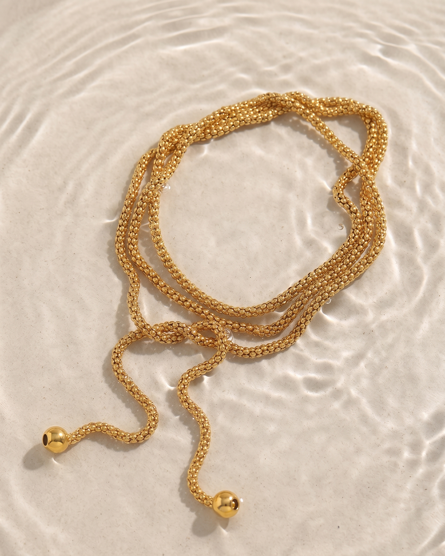 Gold necklace on a textured beige surface