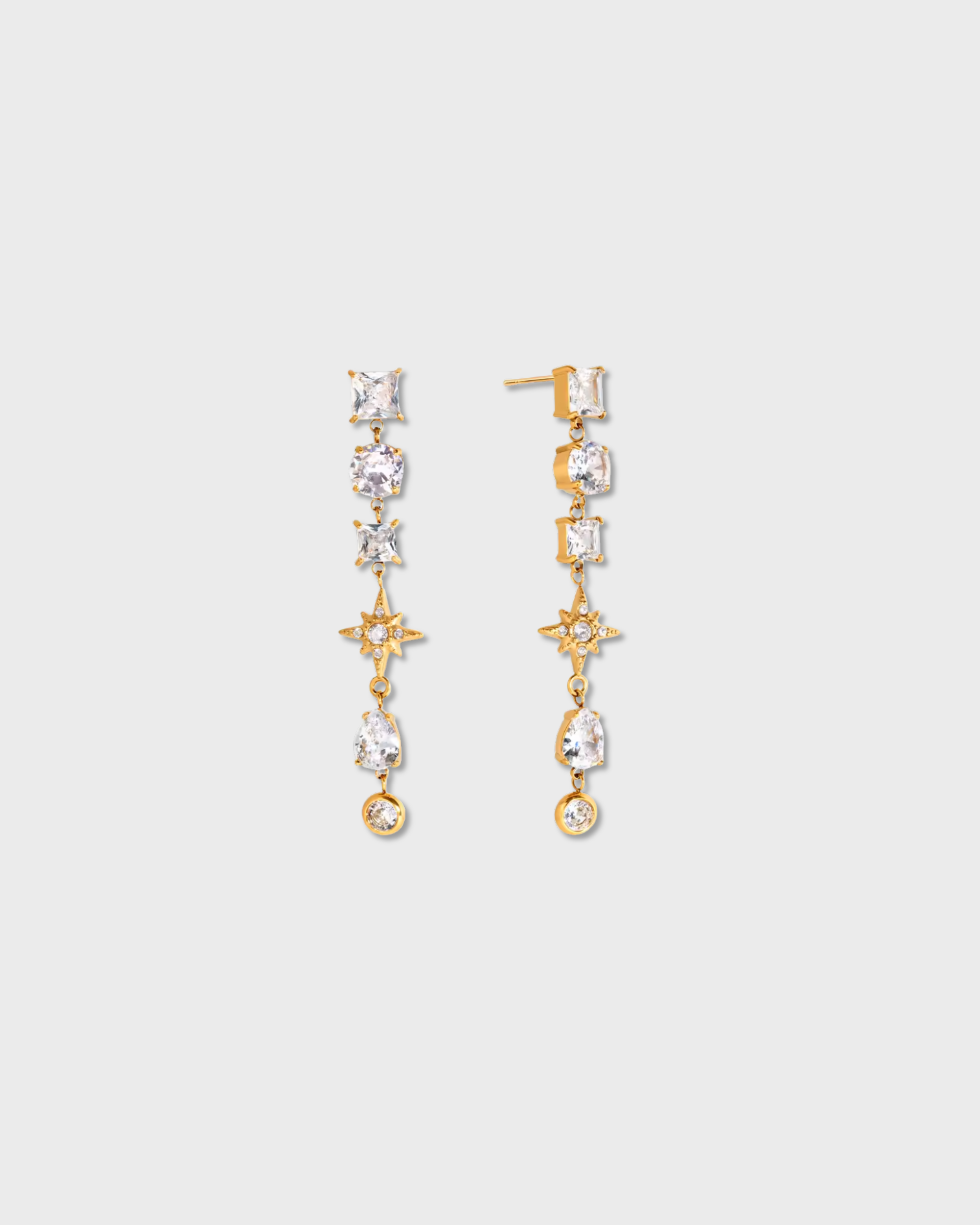 Gold and crystal drop earrings on a light gray background