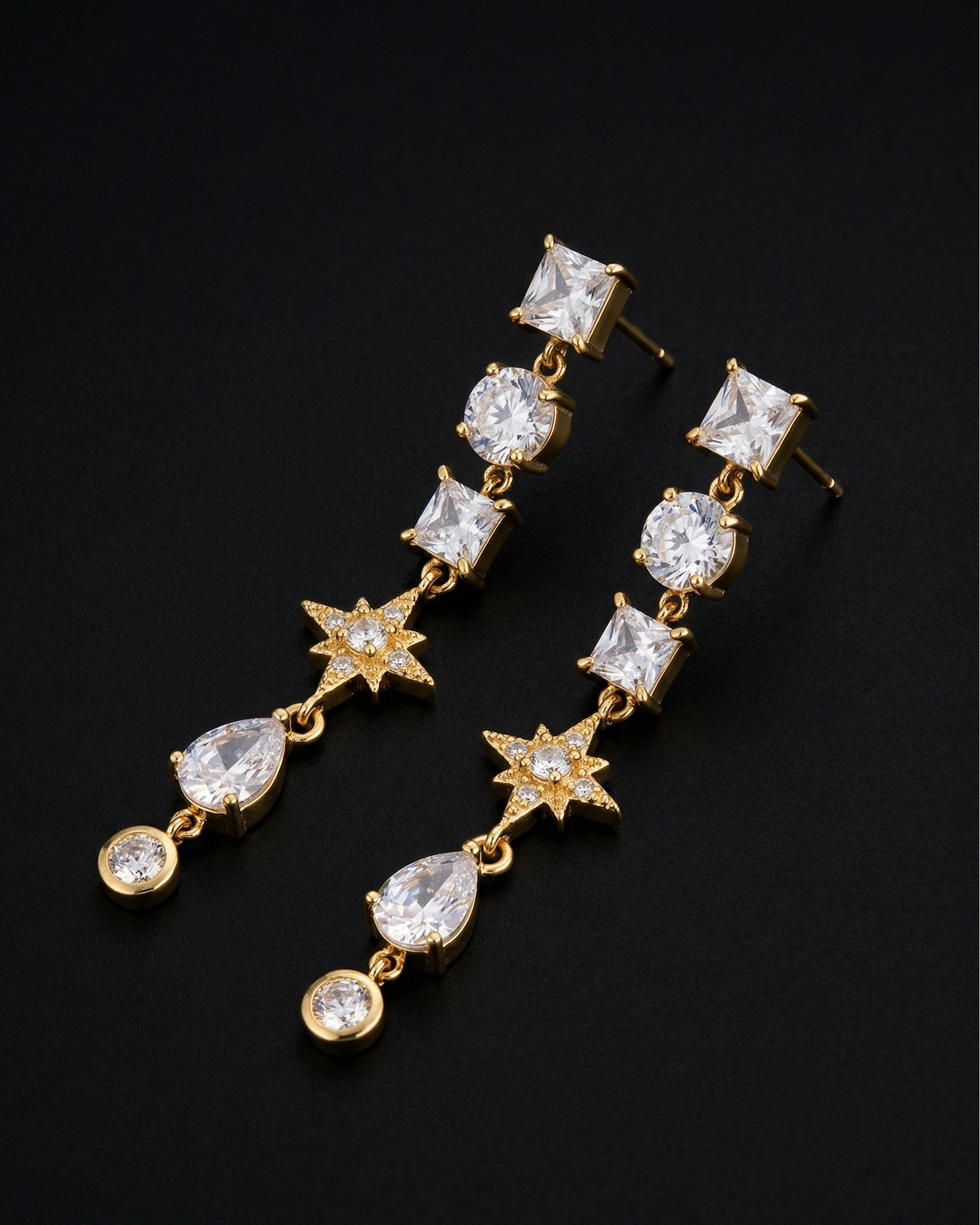Gold earrings with clear gemstones on a black background
