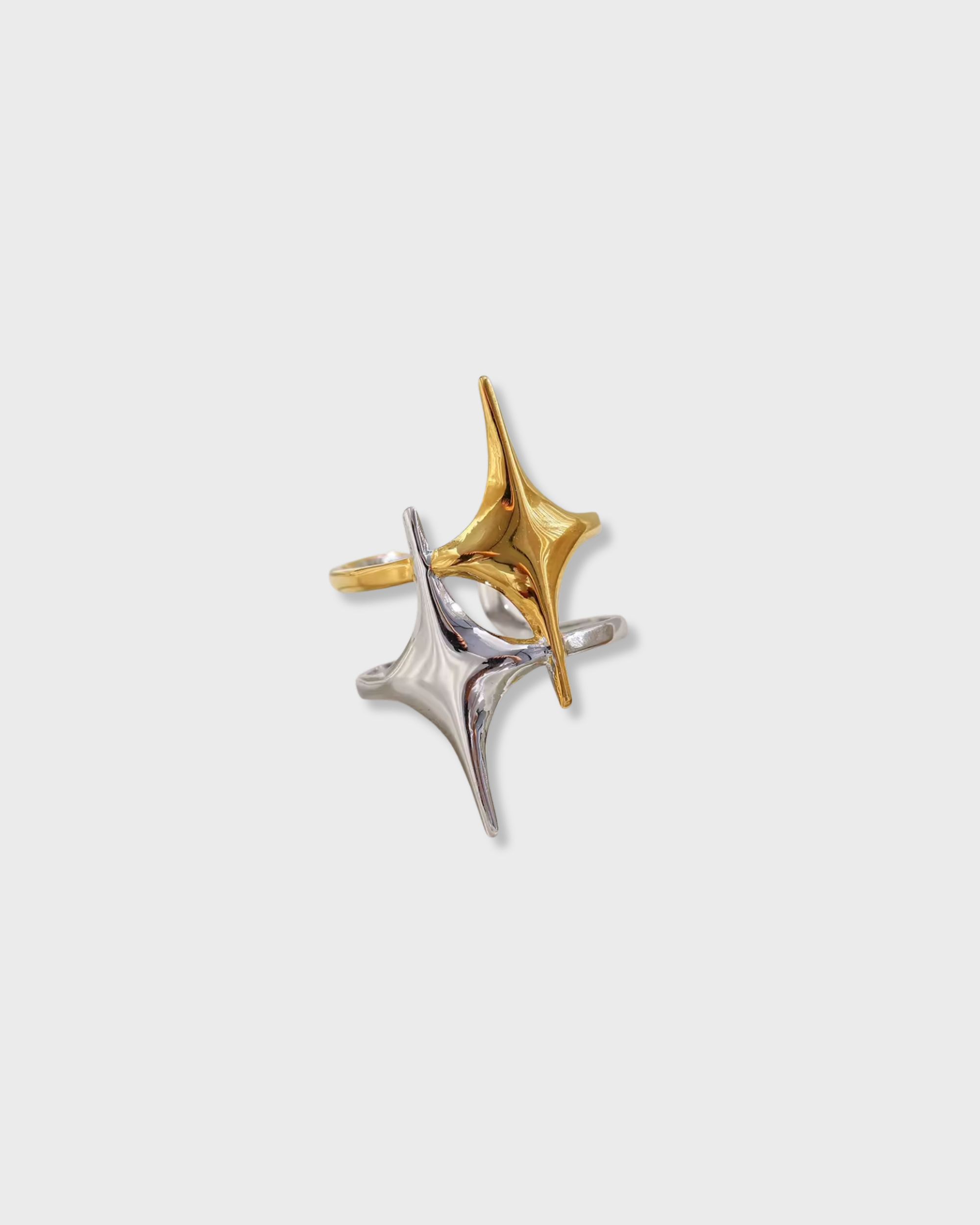 Two star-shaped earrings, one gold and one silver, on a light gray background.