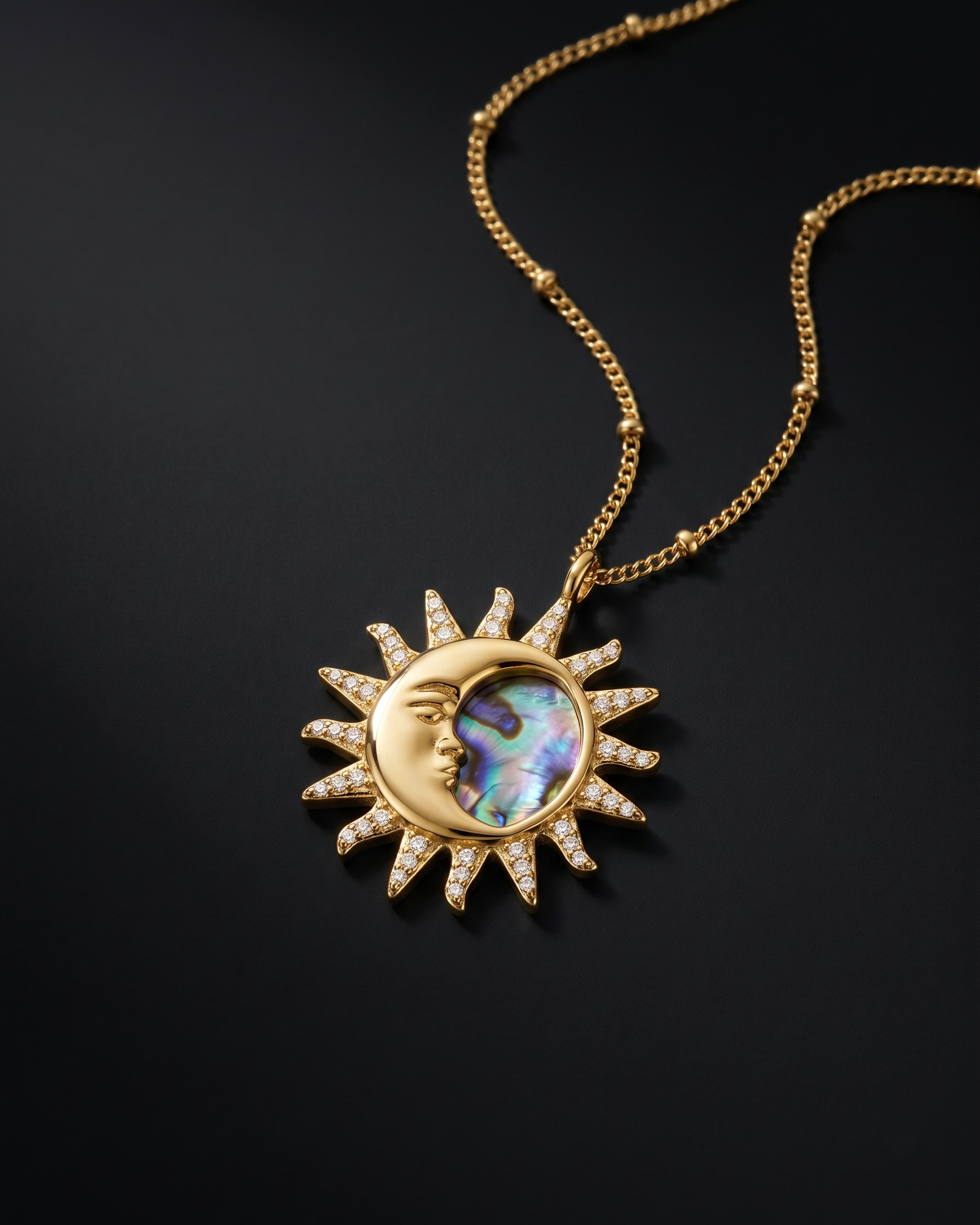 Gold necklace with a sun and moon pendant on a black background