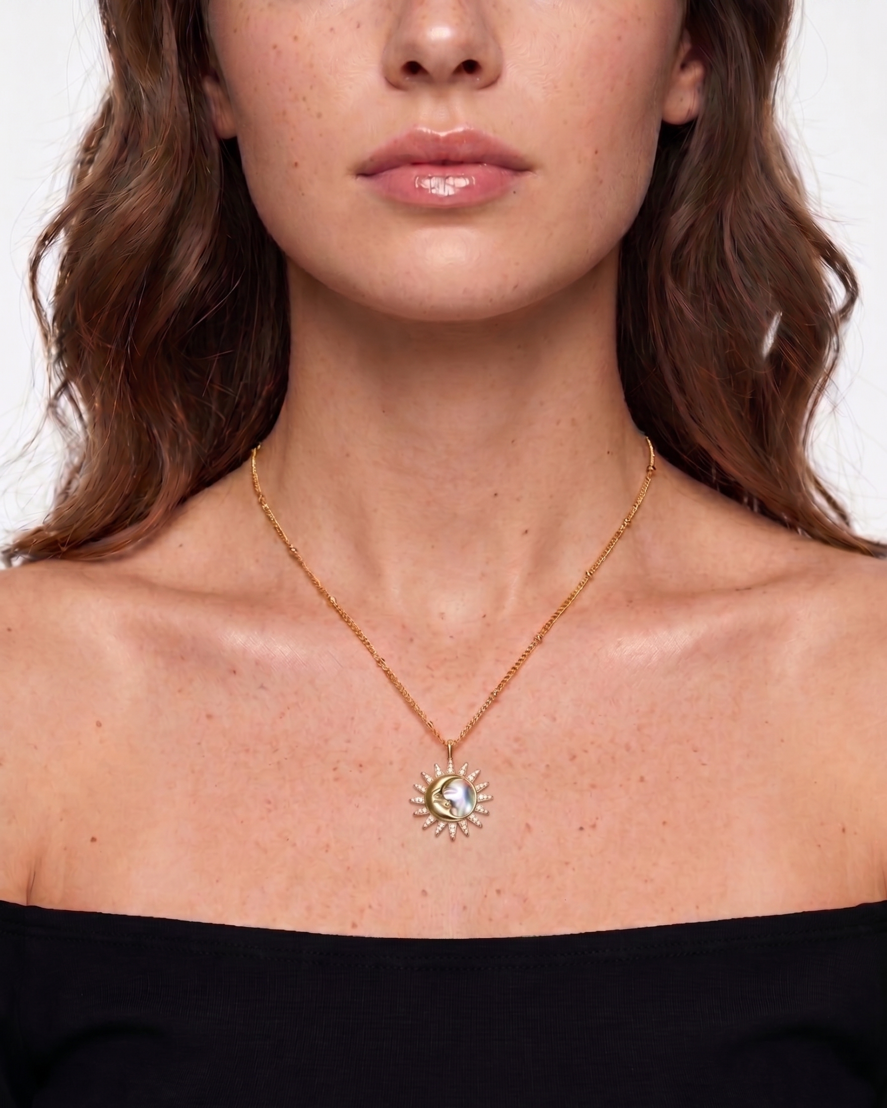 Woman wearing a gold necklace with a sun pendant on a plain background