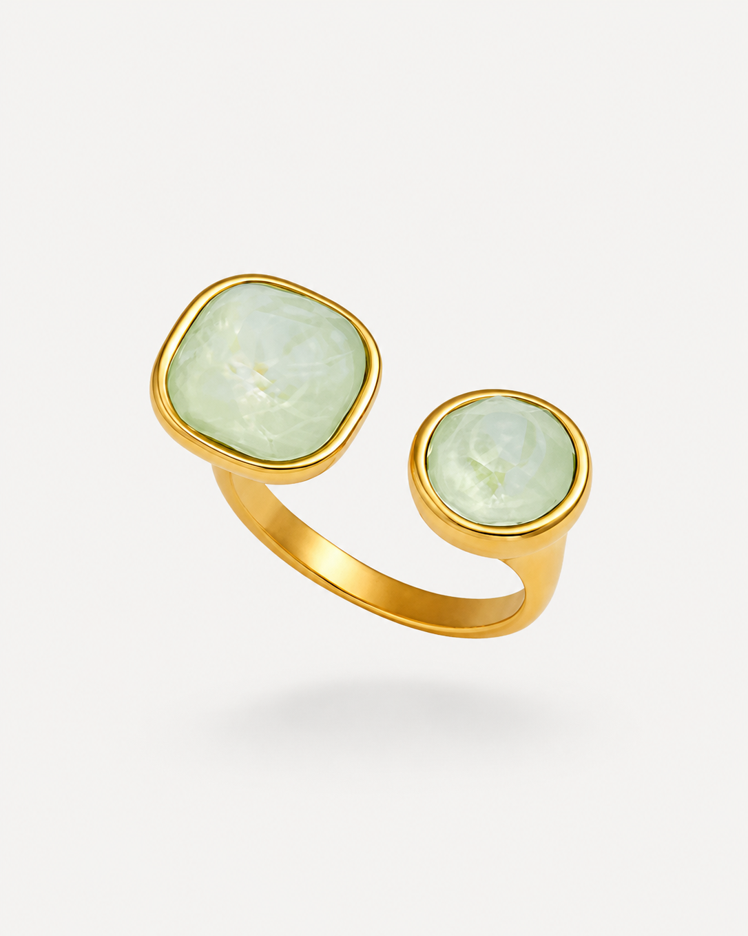 A gold ring with two bezel-set oval stones, one larger square-shaped stone and one smaller round stone, both in a pale green iridescent finish, shown on a light gray background.