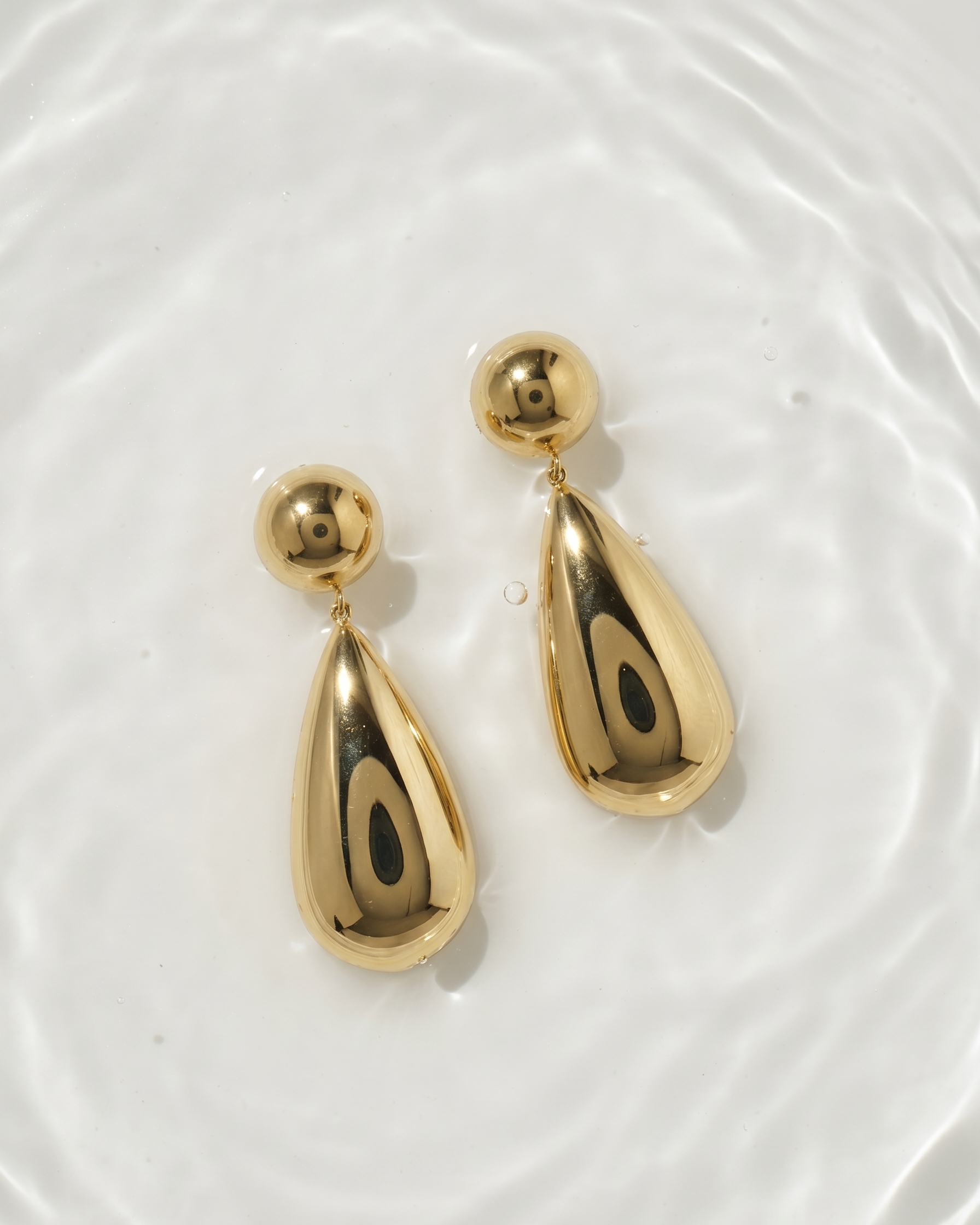 Gold teardrop earrings on a white background