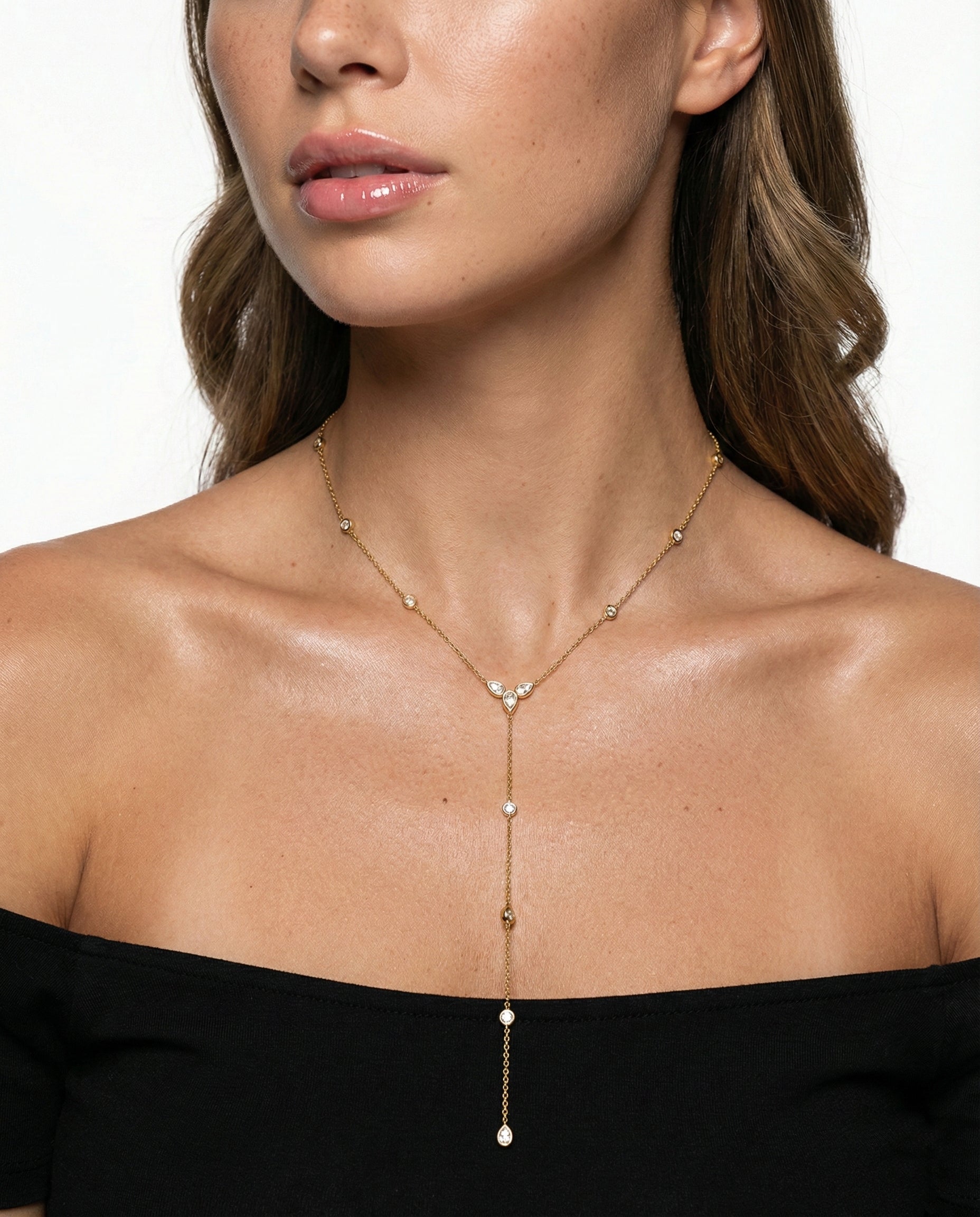 Woman wearing a delicate gold necklace with small beads on a plain background
