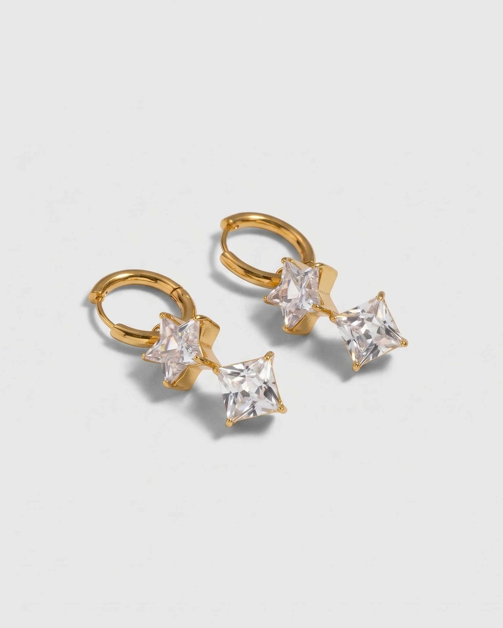 Gold hoop earrings with clear gemstones on a light gray background