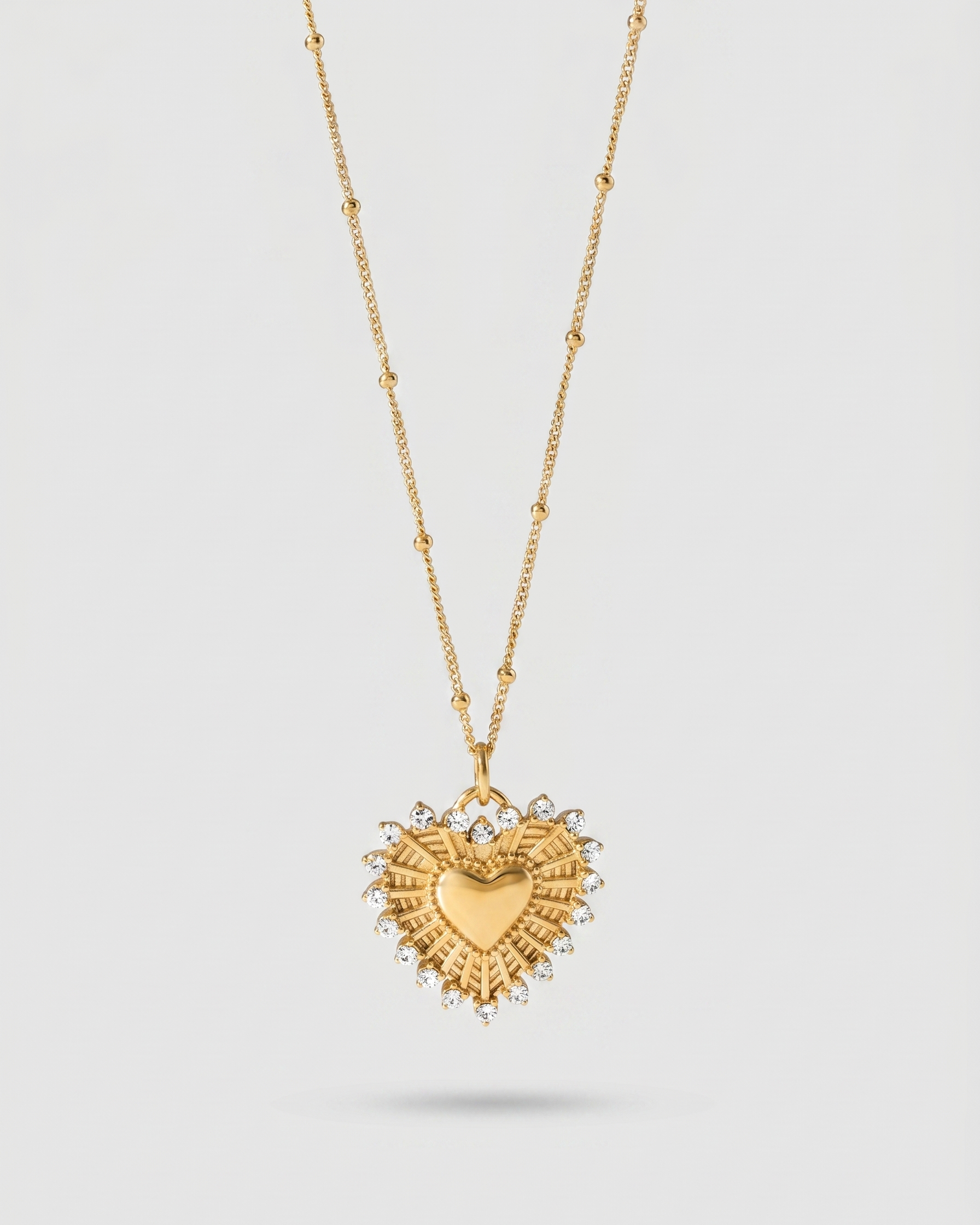 Gold heart-shaped pendant necklace on a light gray background