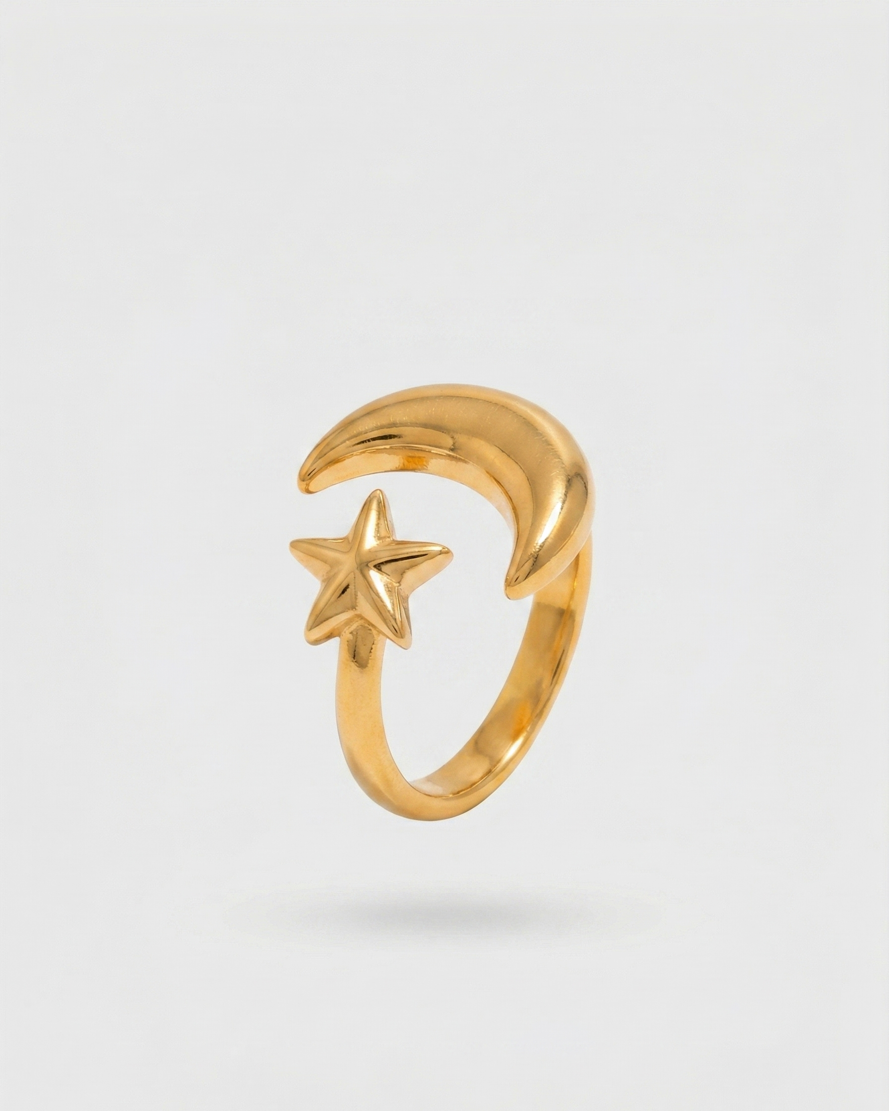 Gold ring with moon and star design on a light gray background