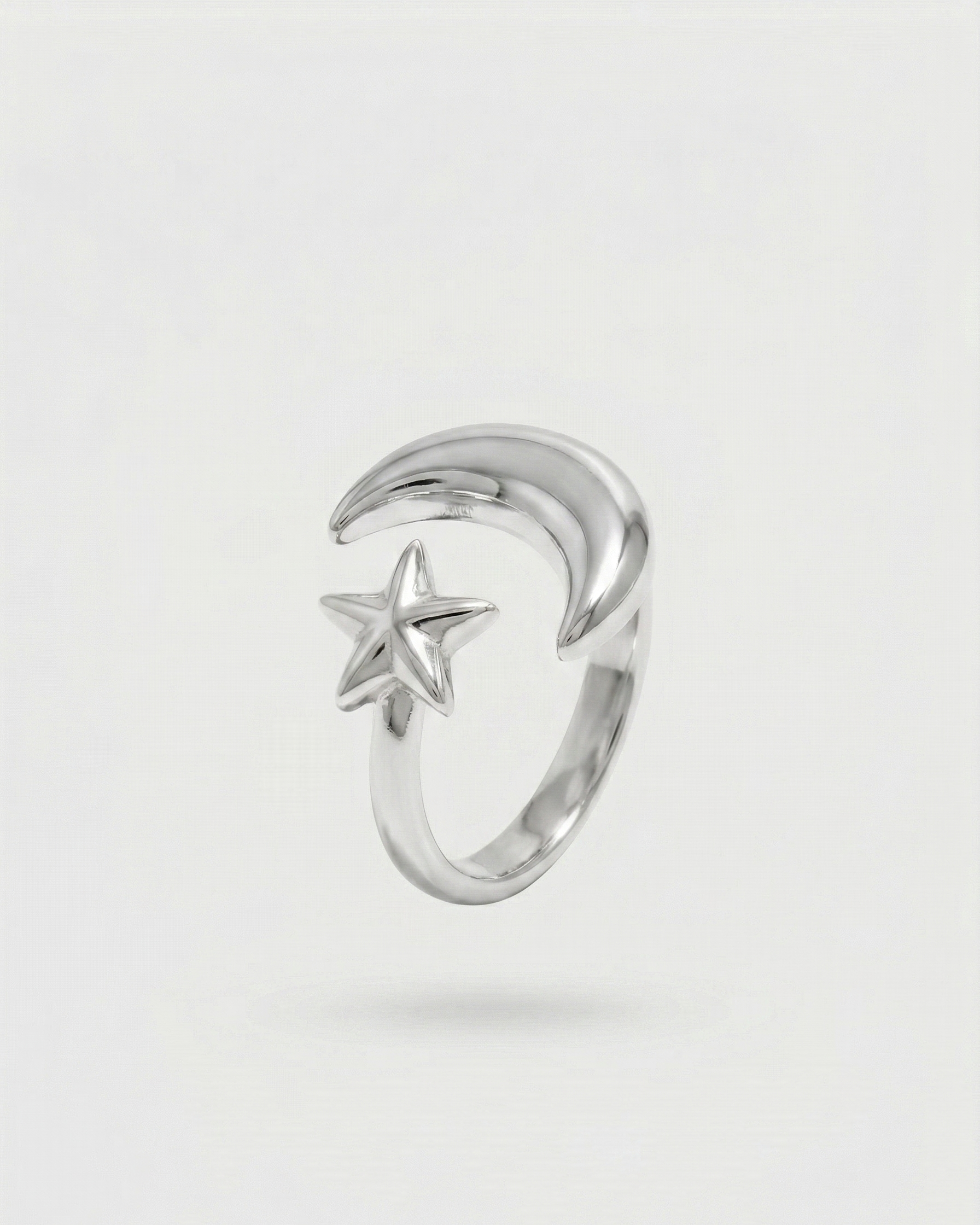 Silver ring with moon and star design on a light gray background
