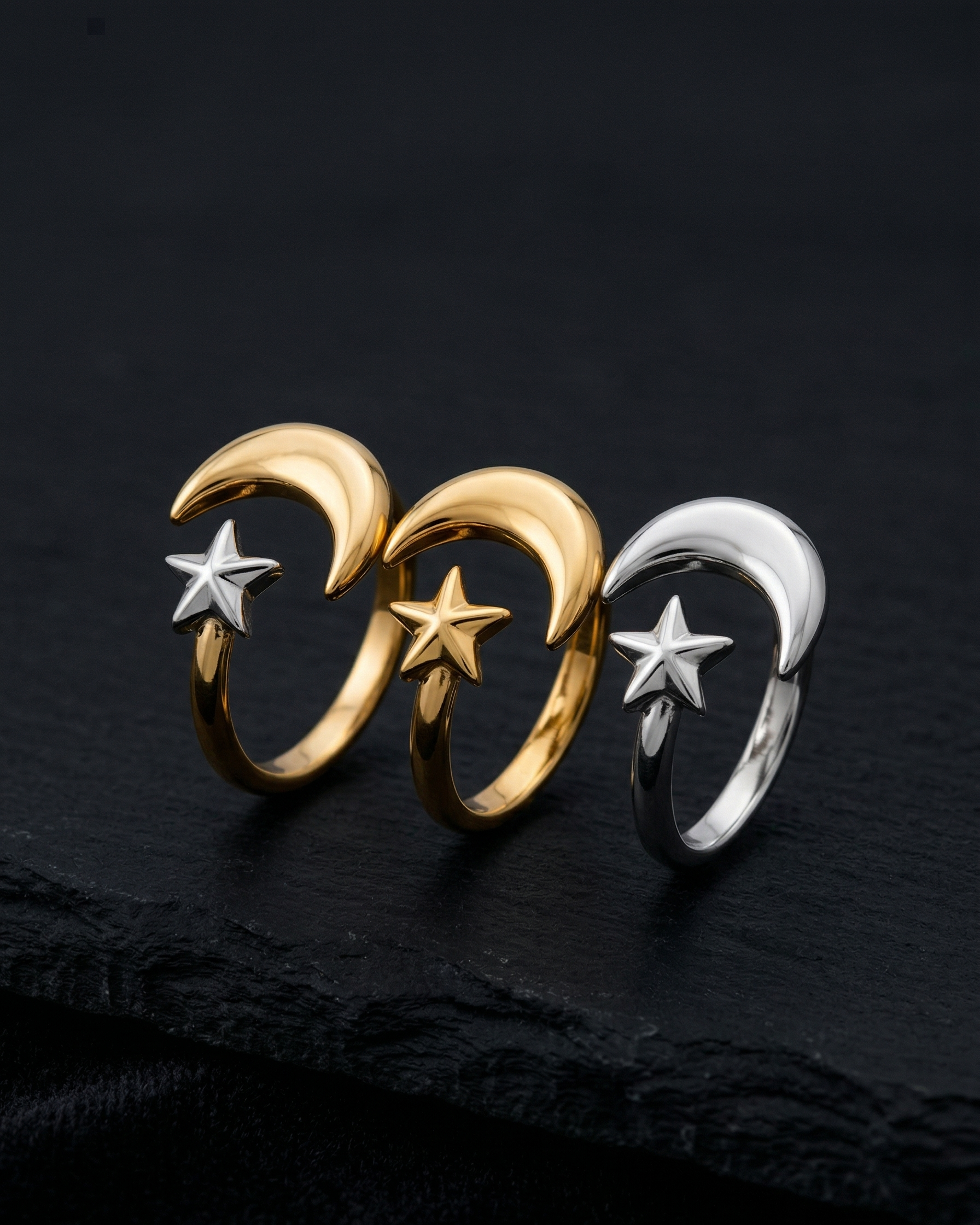 Three rings with moon and star designs on a dark background