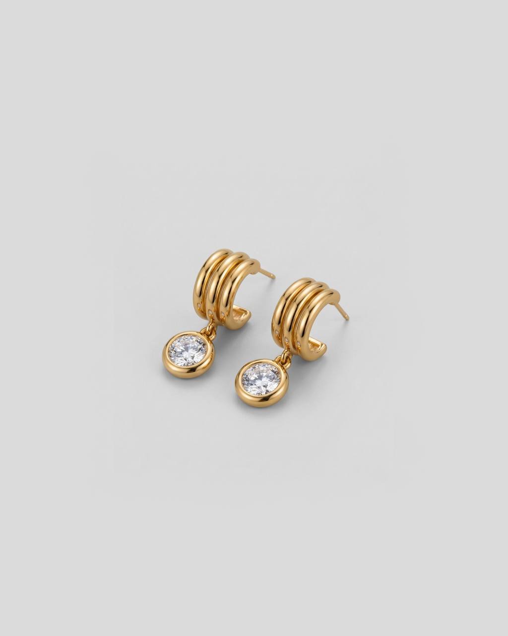 Gold hoop earrings with small round gemstones on a light gray background