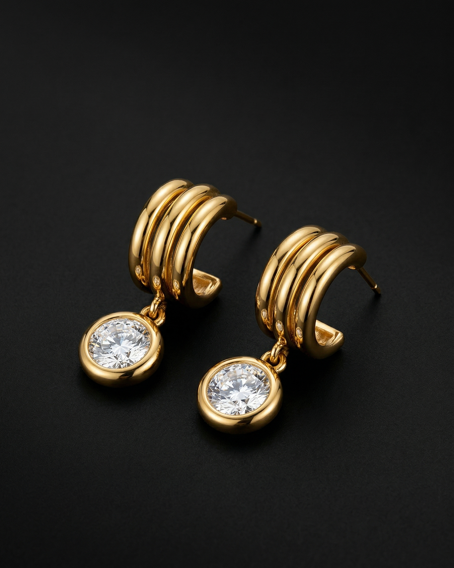 Gold hoop earrings with clear gemstones on a black background