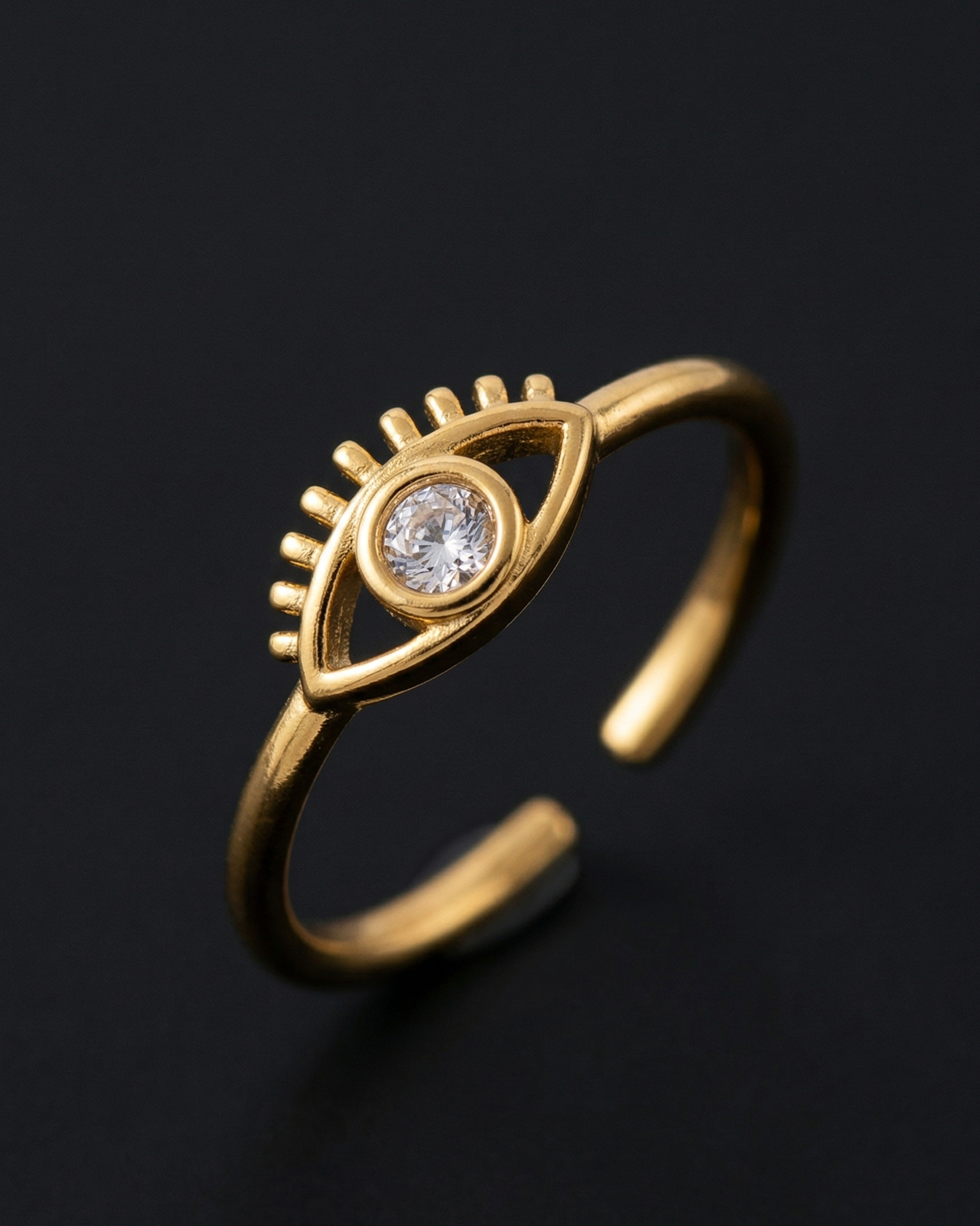 Gold ring with eye design and diamond on a black background