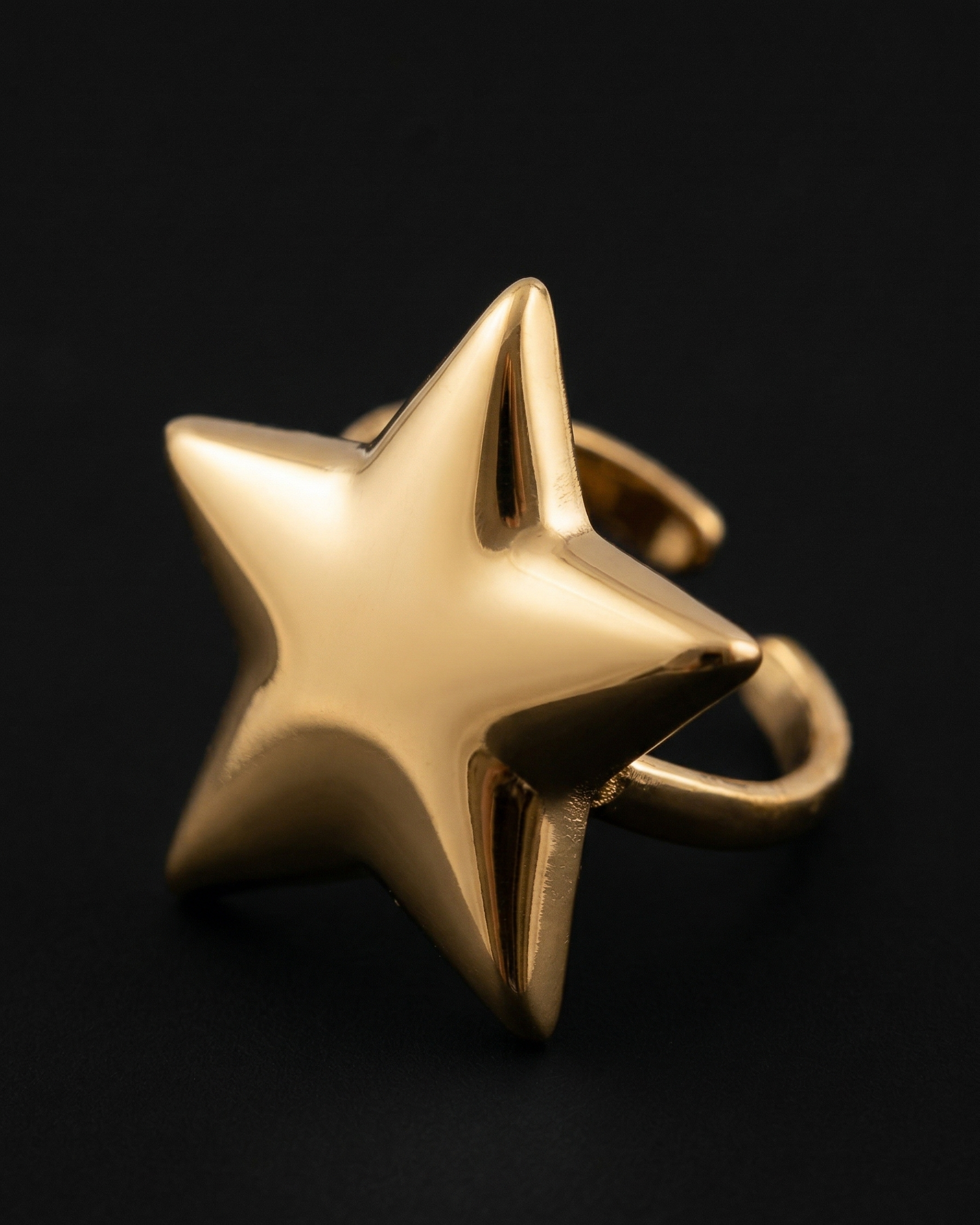 Gold star-shaped ring on a black background