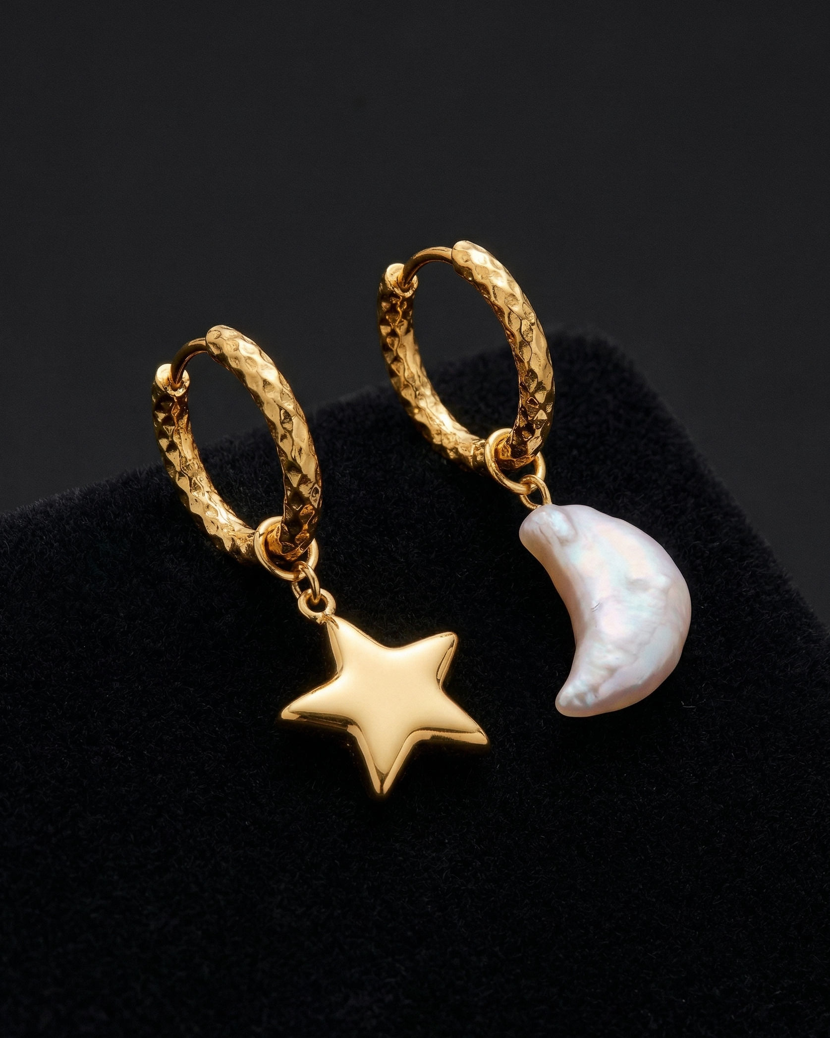 Gold hoop earrings with star and moon charms on a black background