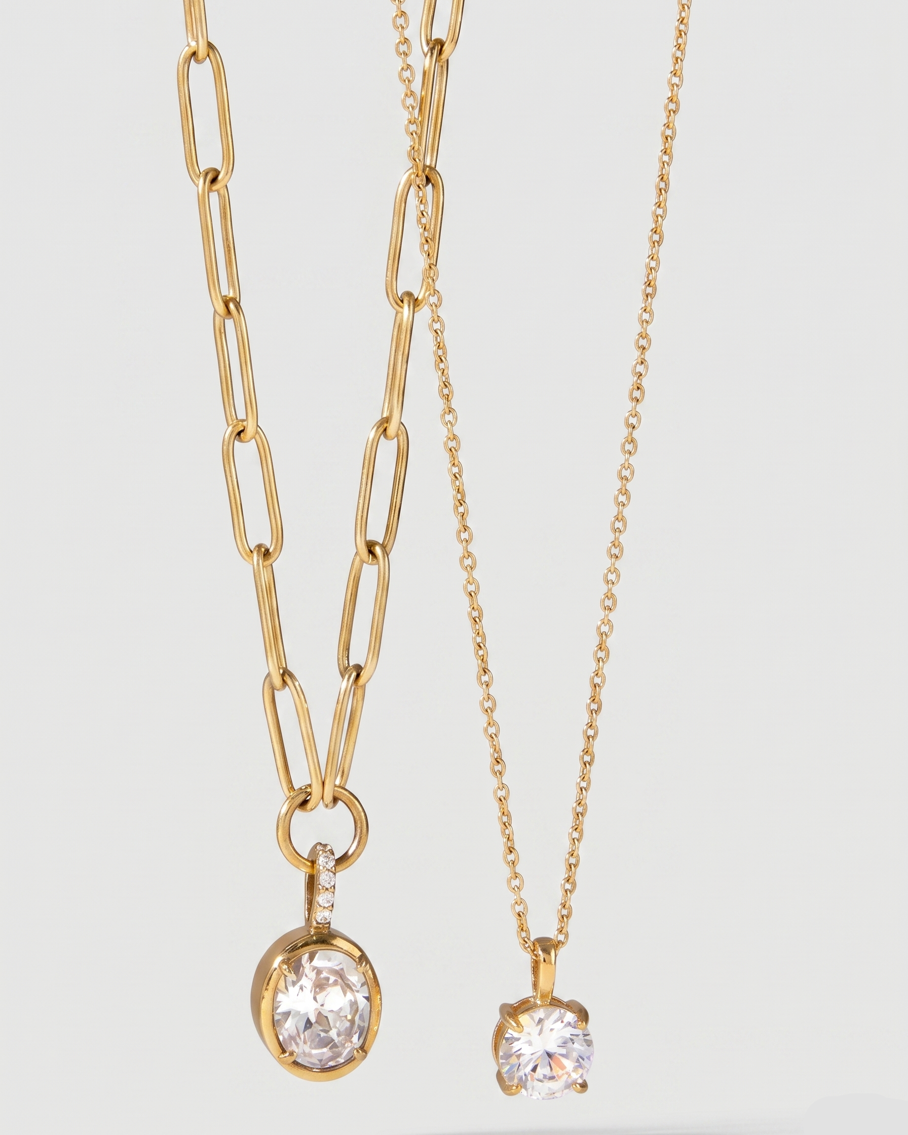 Two gold necklaces with pendant stones on a light gray background