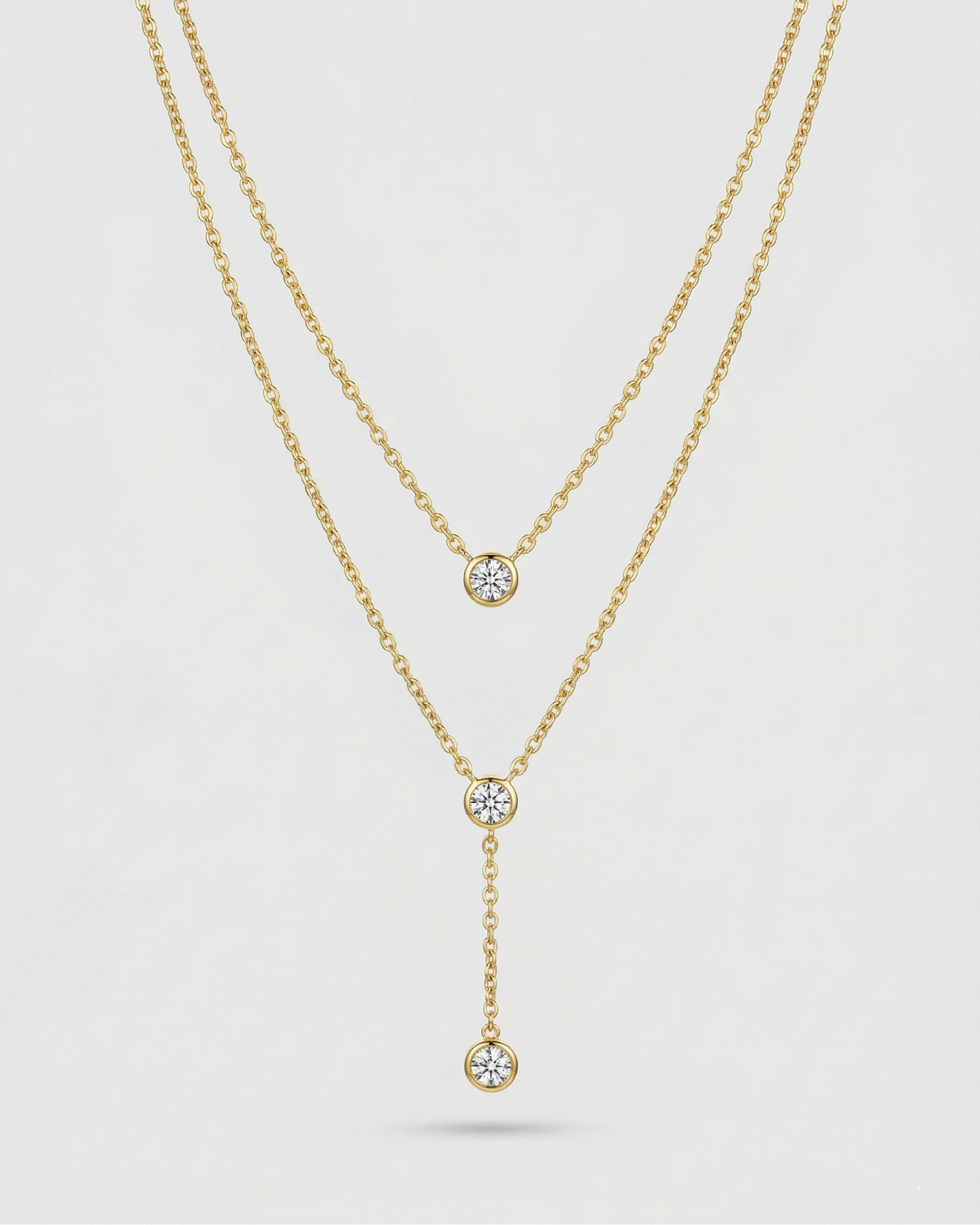 Gold necklace with diamond pendants on a light gray background