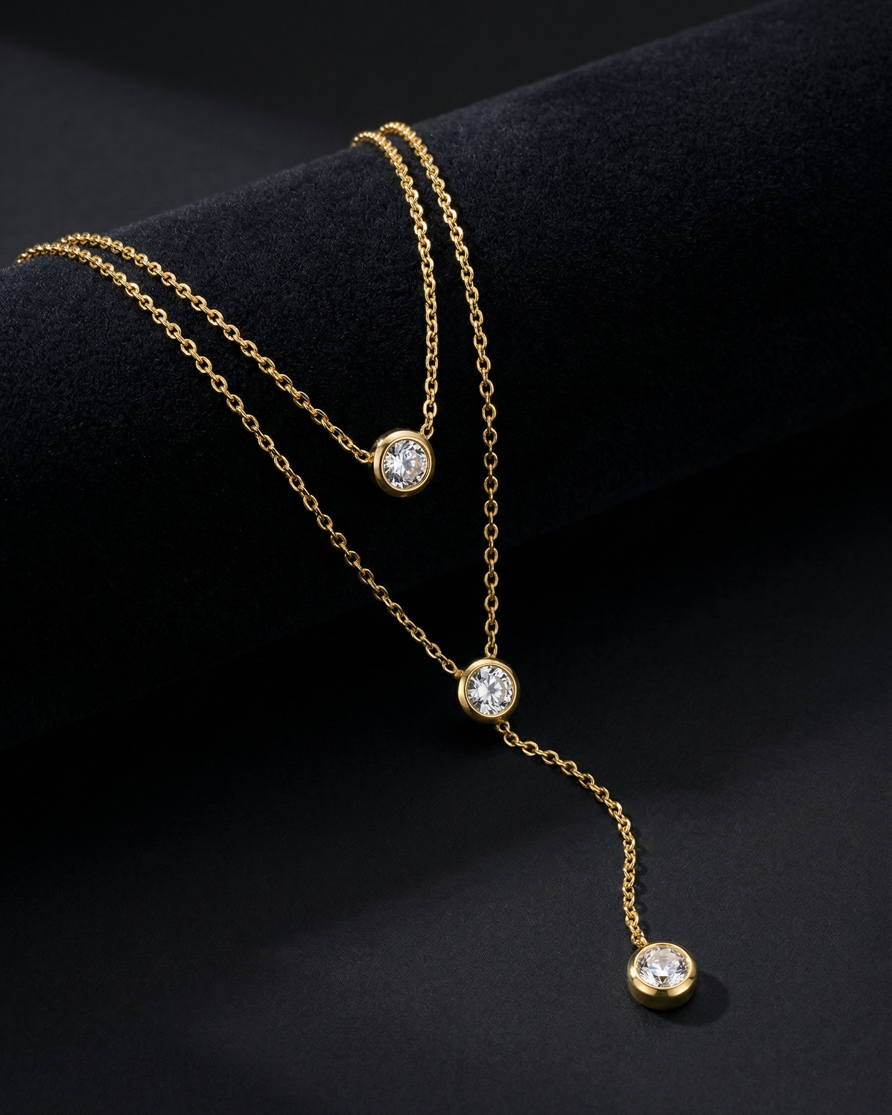 Gold necklace with three diamond pendants on a black background