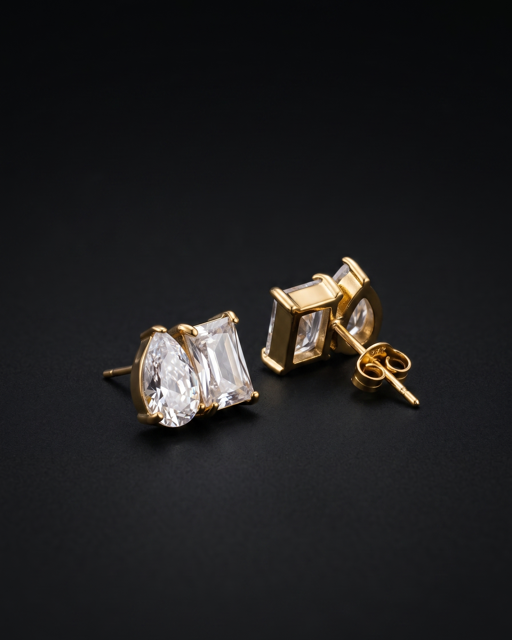 Gold earrings with clear gemstones on a black background