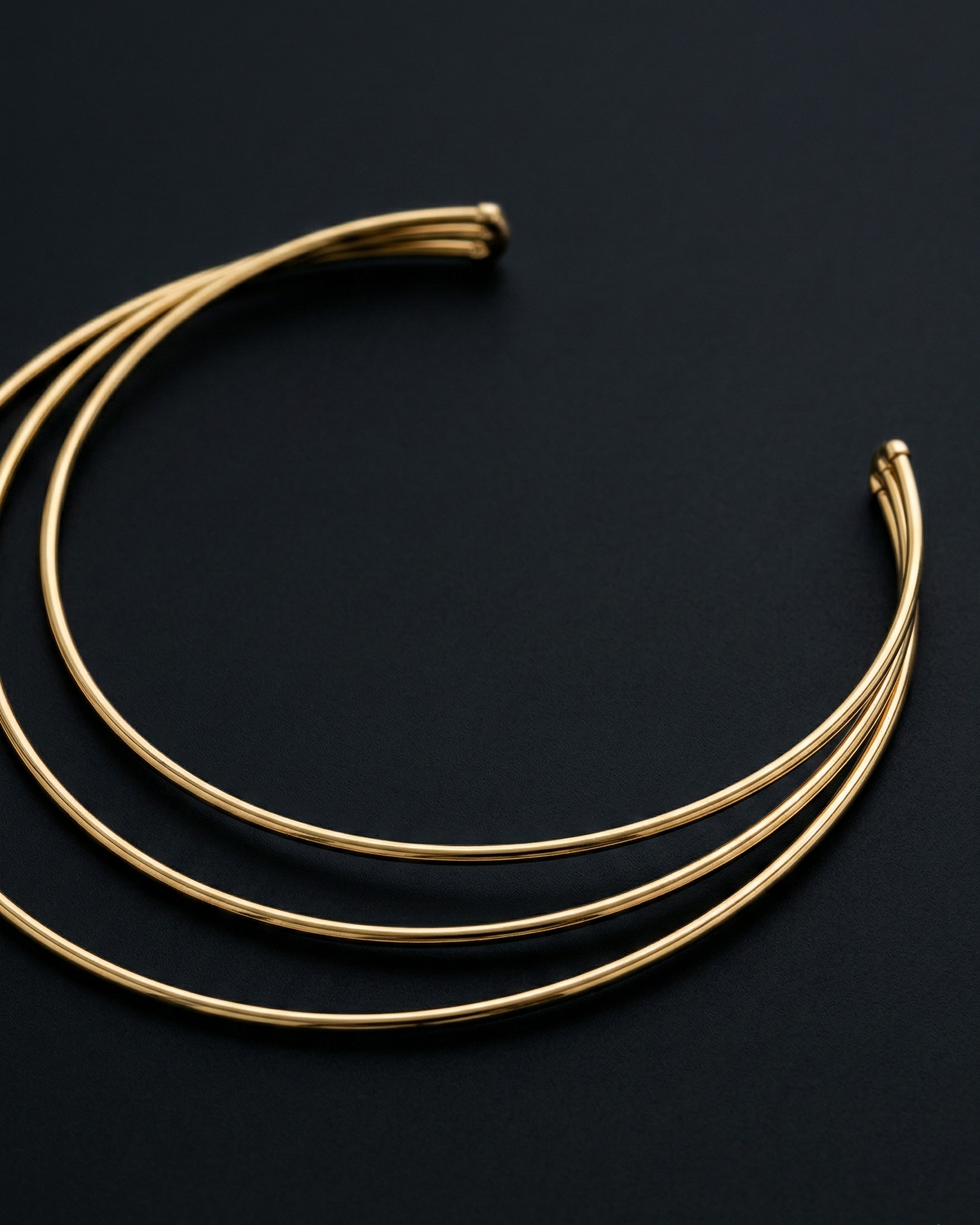 Three gold necklaces on a black background