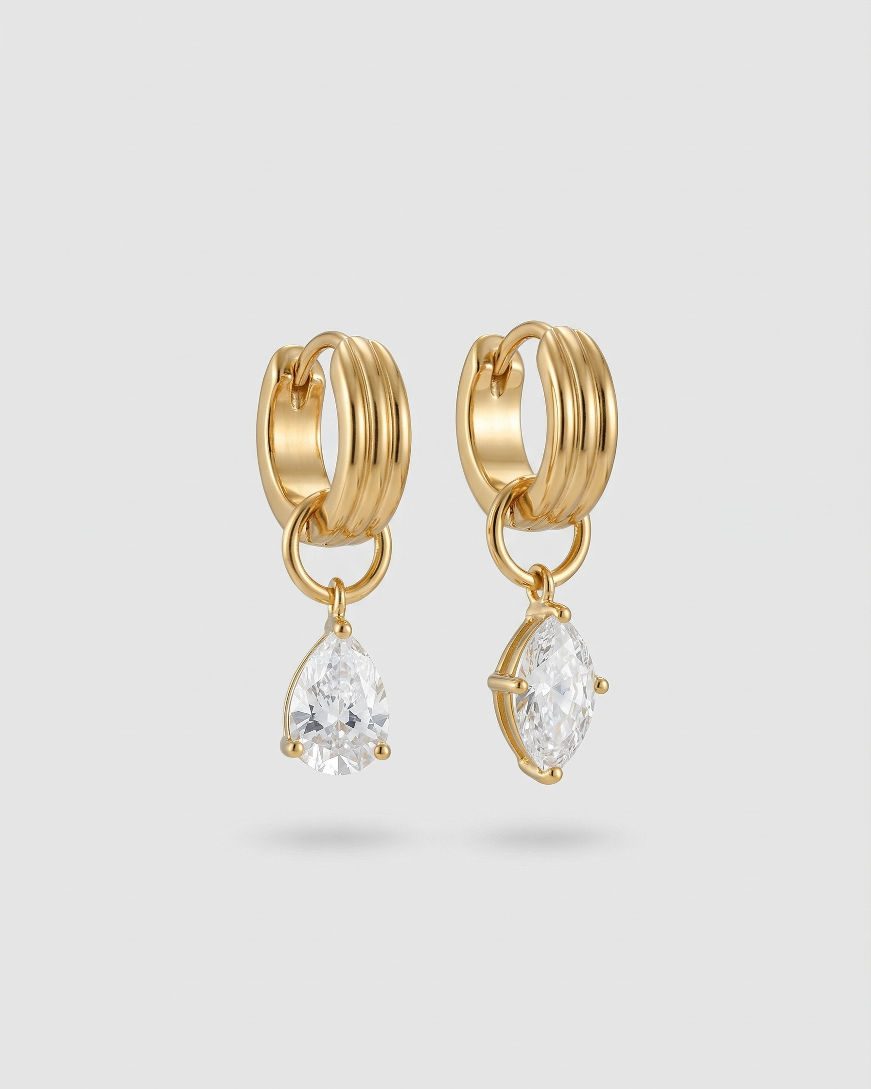 Gold hoop earrings with teardrop-shaped gemstones on a light gray background
