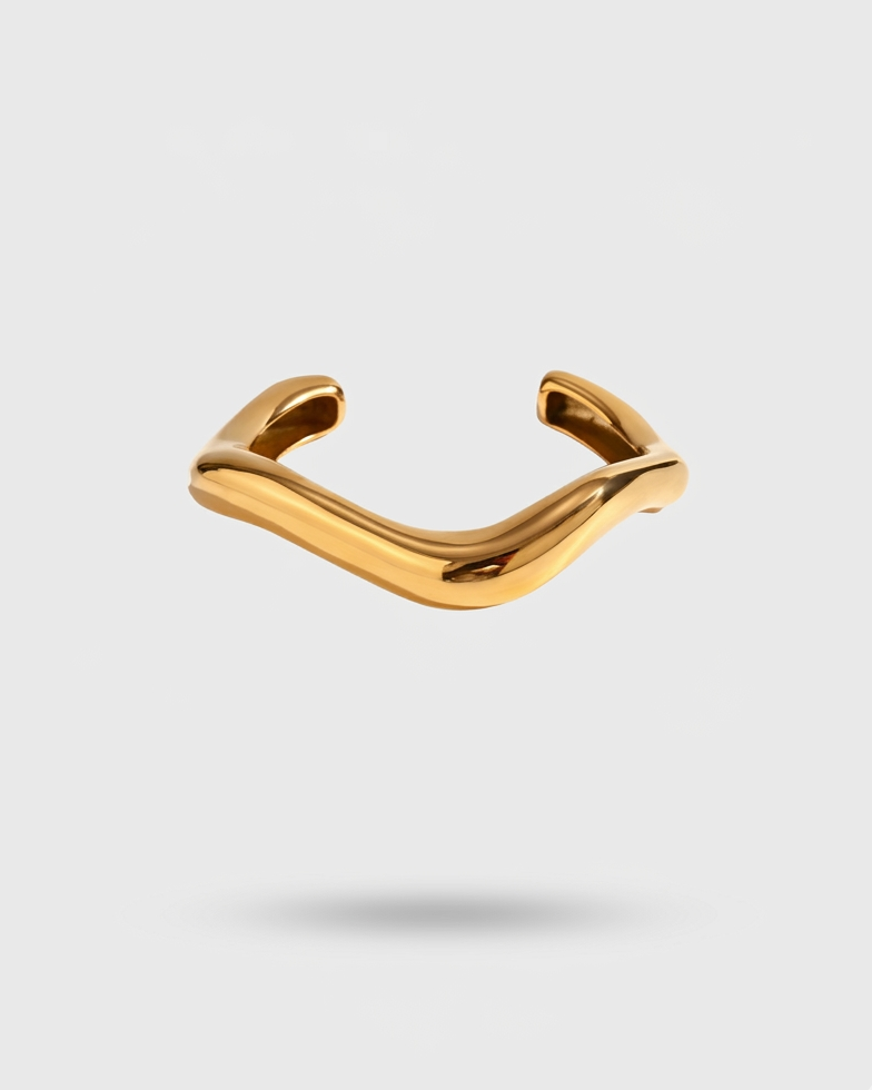 Gold ring with a wavy design on a light gray background
