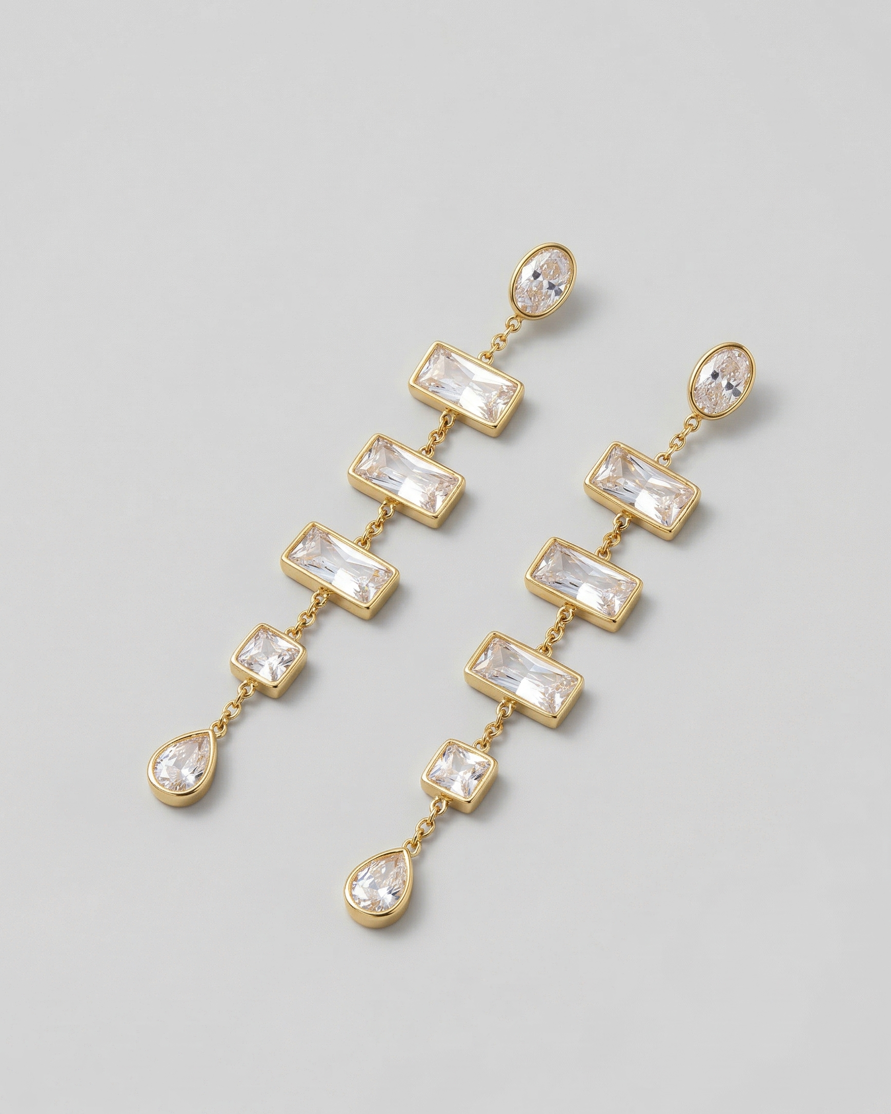 Gold and crystal drop earrings on a light gray background
