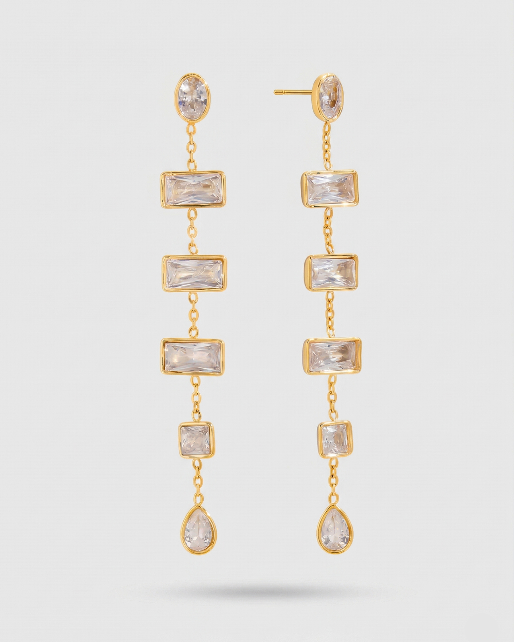 Gold earrings with clear gemstones on a white background
