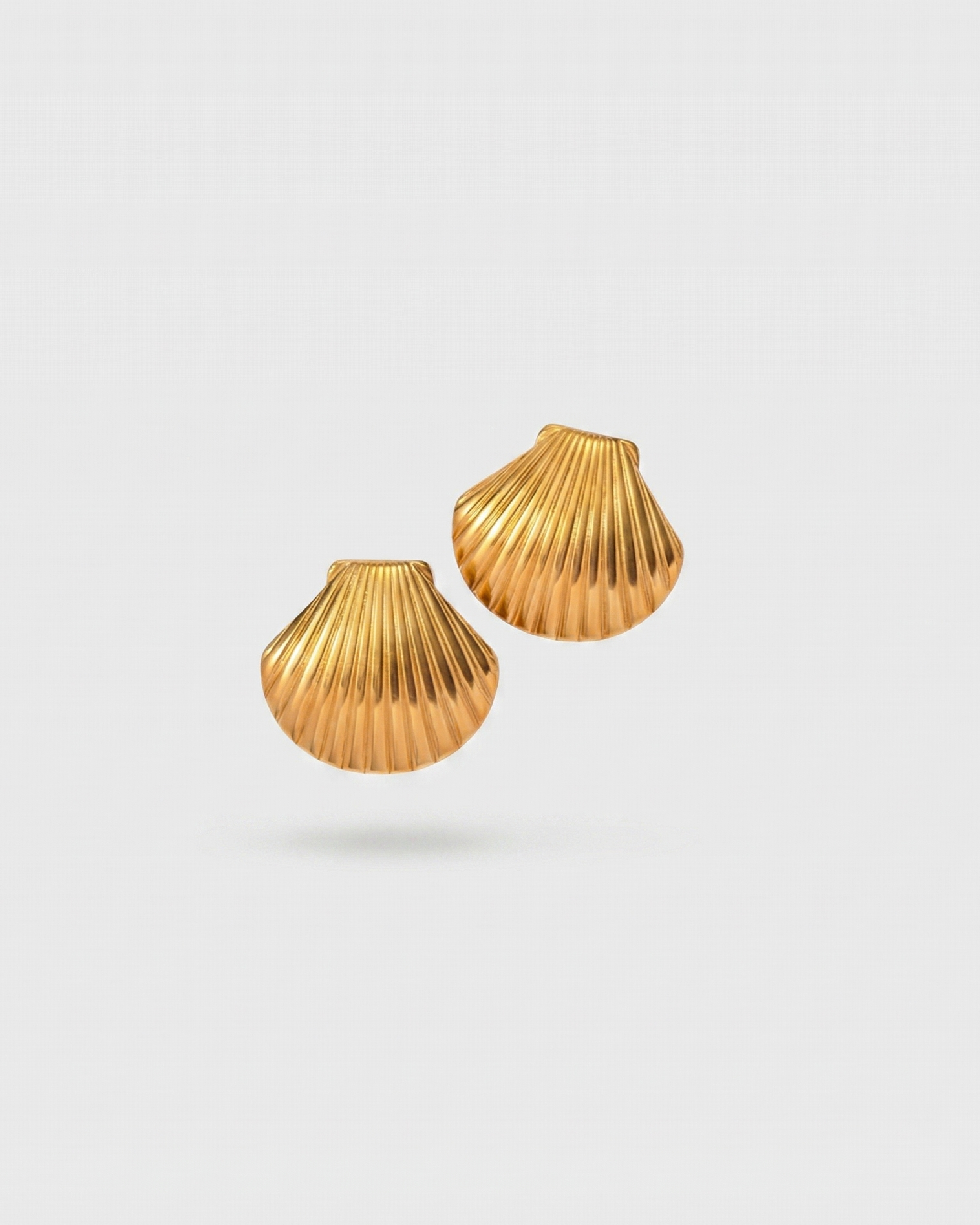 Pair of gold shell-shaped earrings on a light gray background