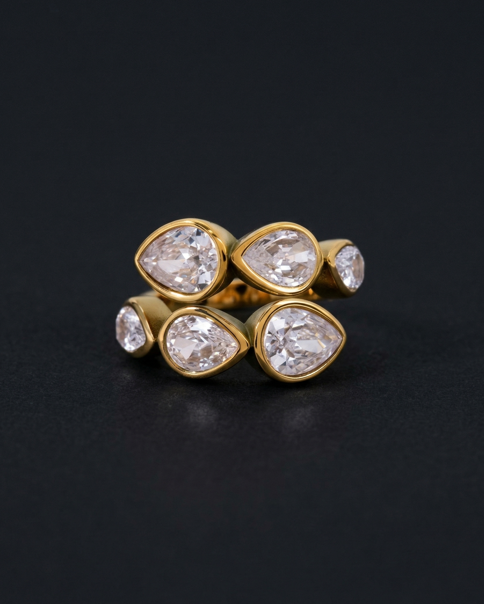 Gold ring with pear-shaped diamonds on a black background