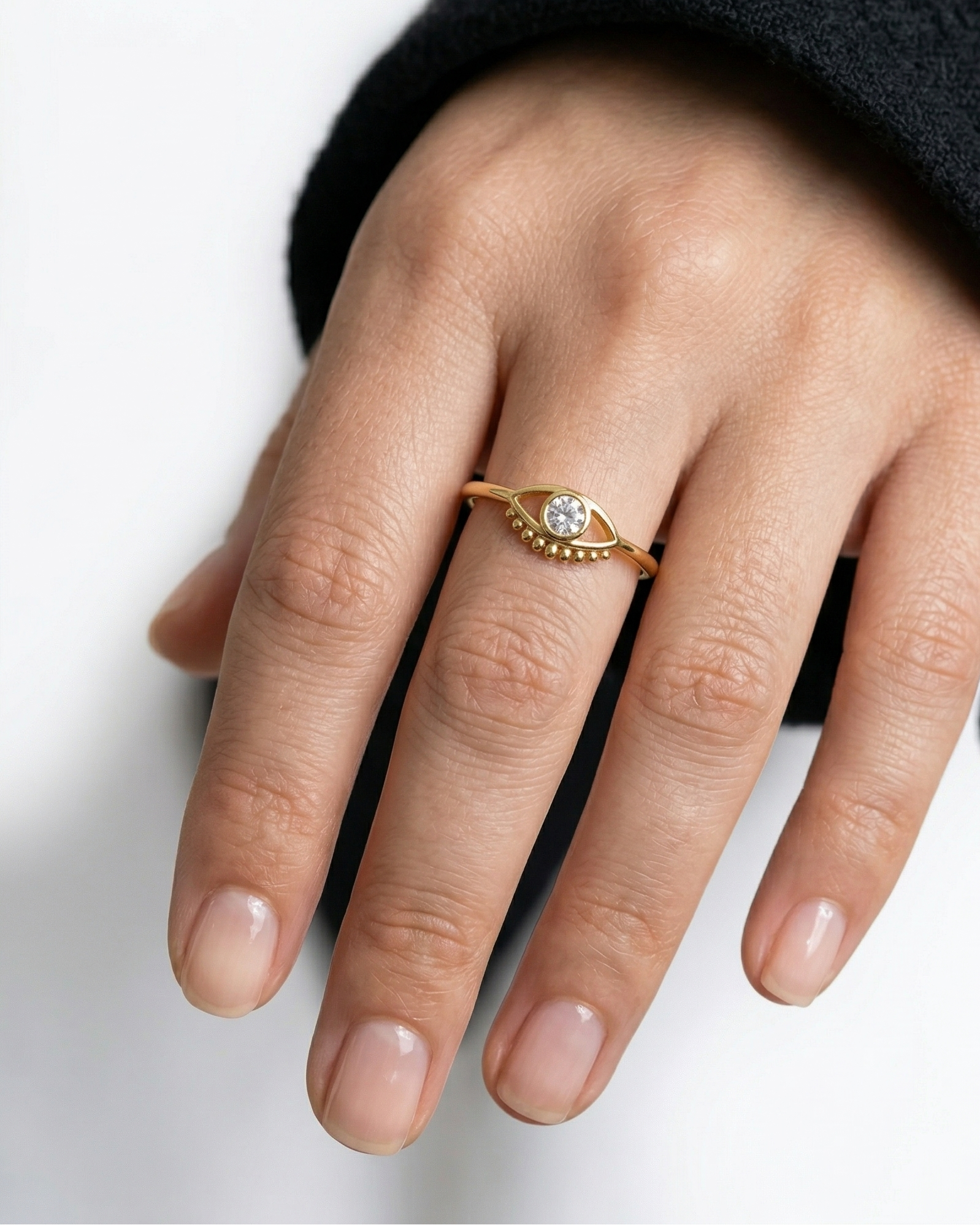 Hand wearing a gold ring with a diamond on a white background