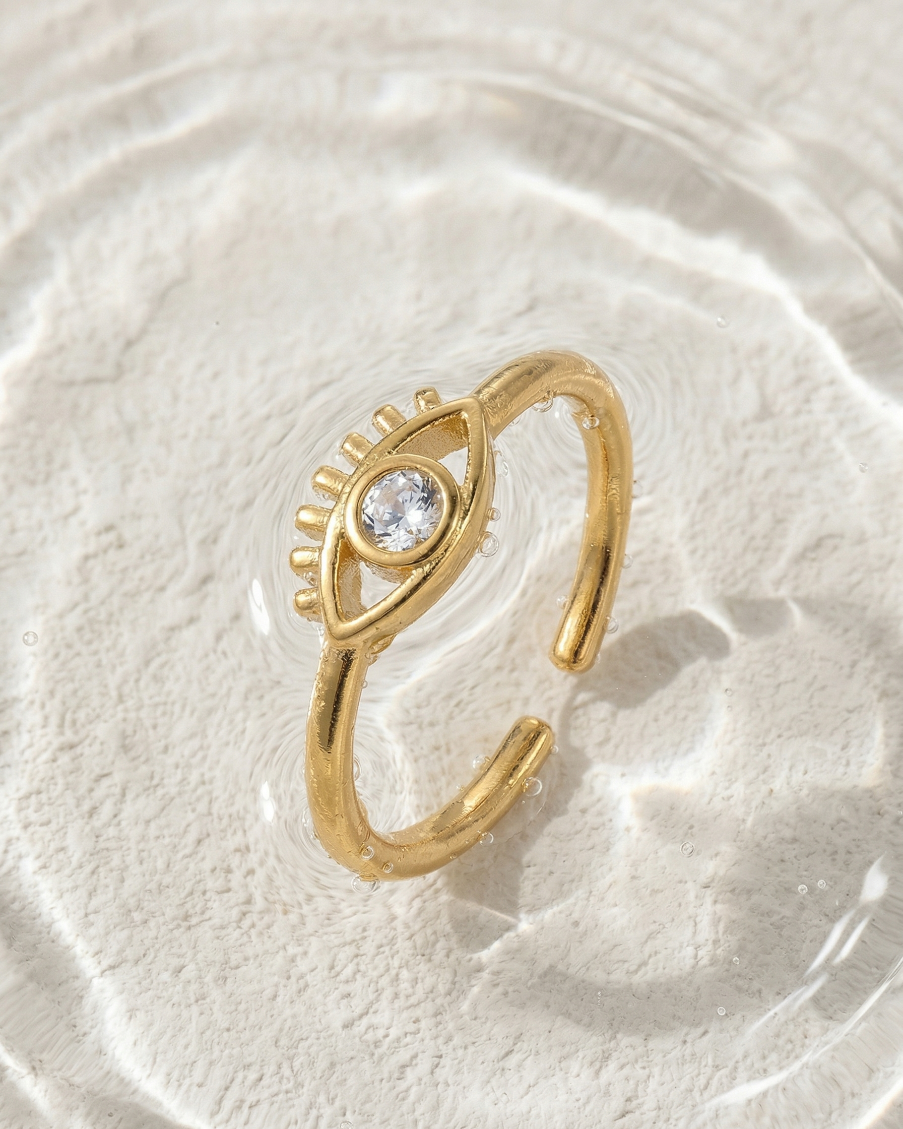Gold ring with a diamond on a textured white surface