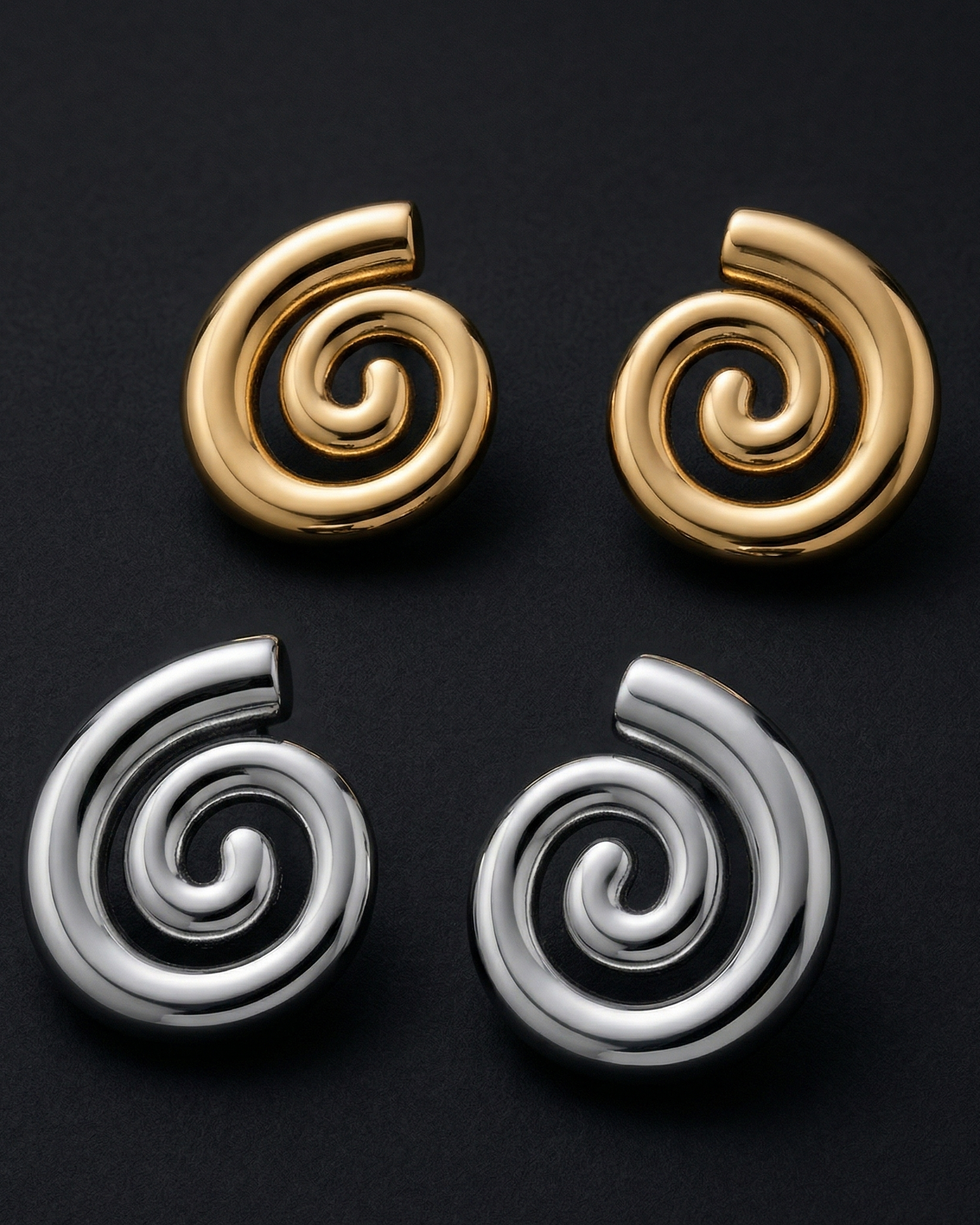 Two pairs of spiral earrings, one gold and one silver, on a black background.