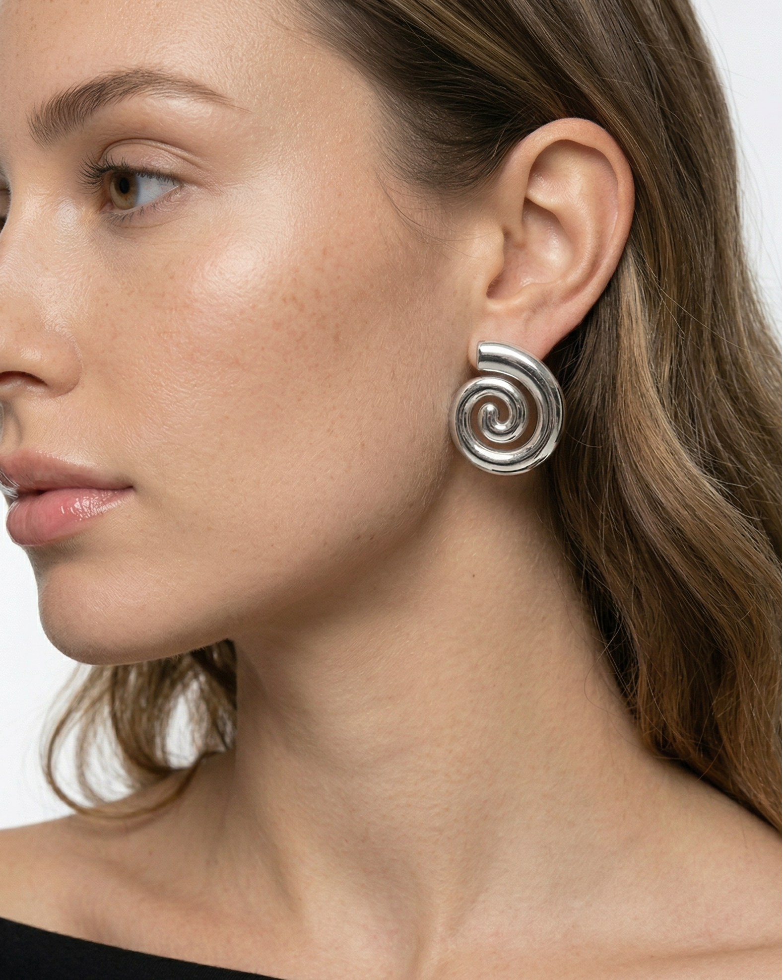 Woman wearing a spiral earring on a plain background