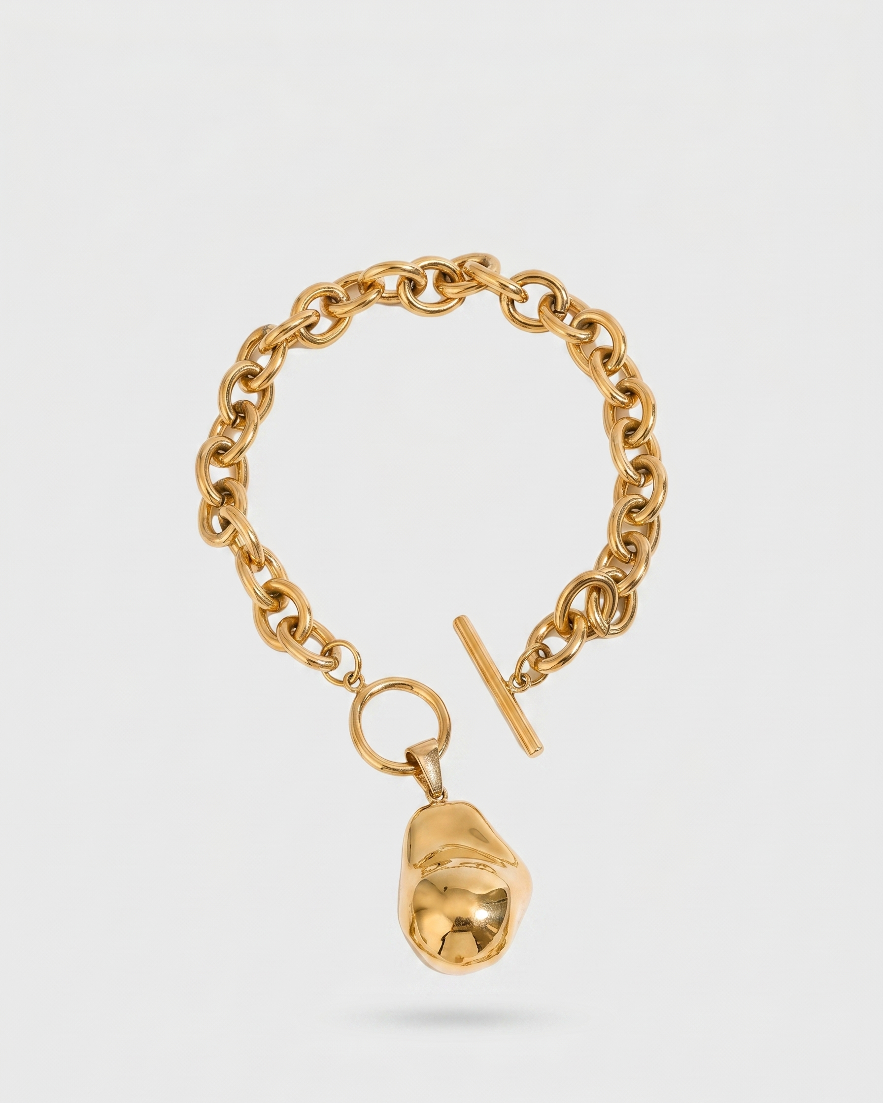 Gold chain bracelet with a unique pendant on a light gray background