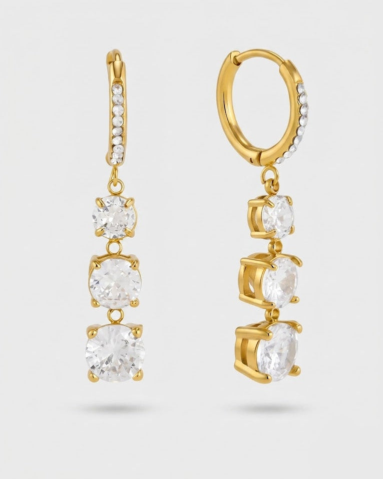 Gold hoop and drop earrings with clear gemstones on a light gray background