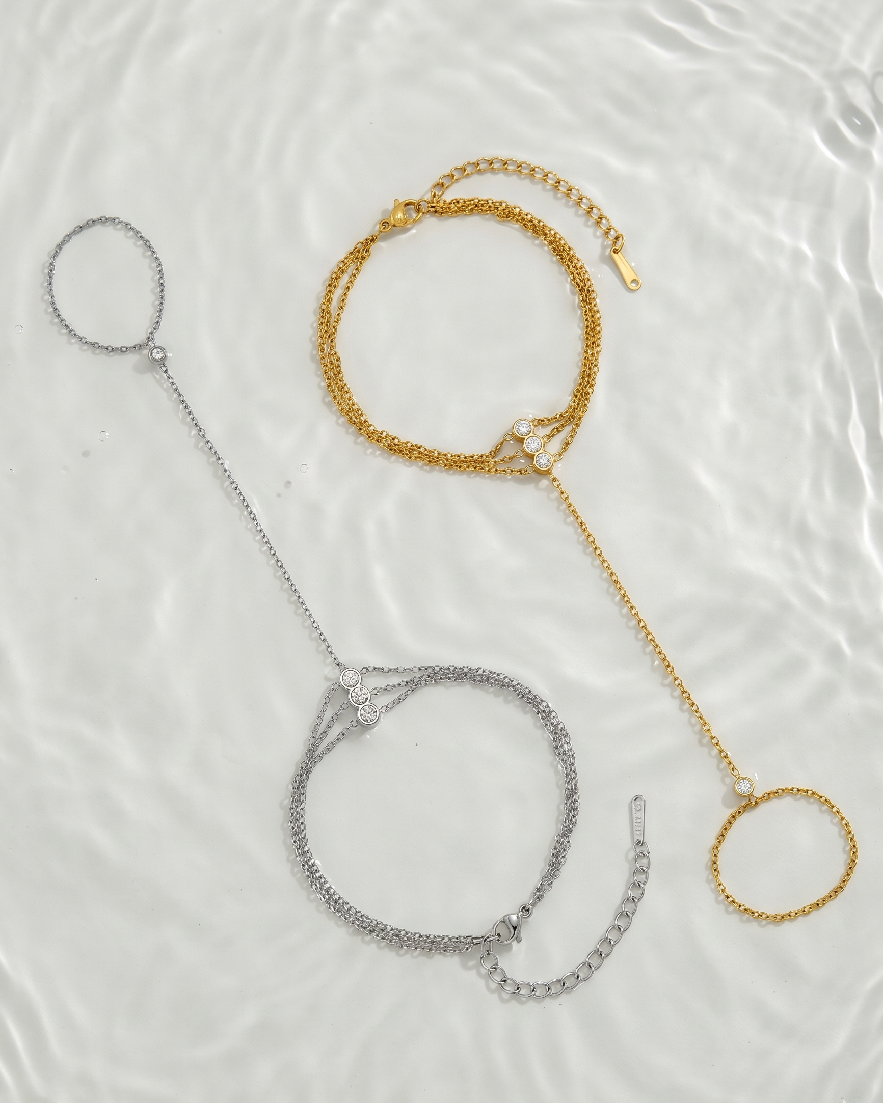 Three bracelets in gold, silver, and rose gold on a textured white surface