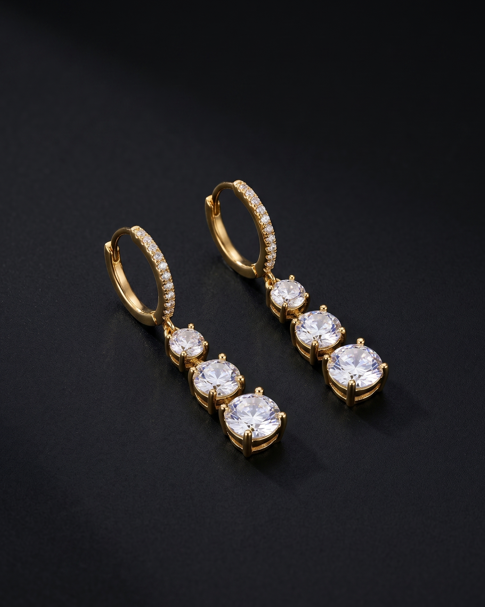 Gold earrings with clear gemstones on a black background