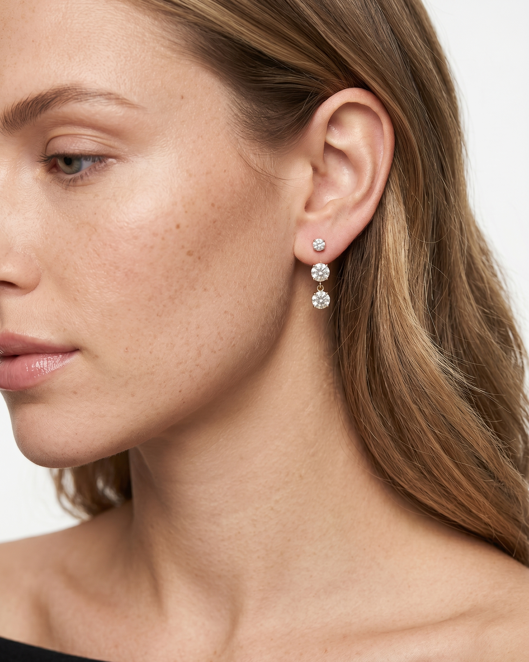 Close-up of a woman wearing diamond earrings with a neutral background