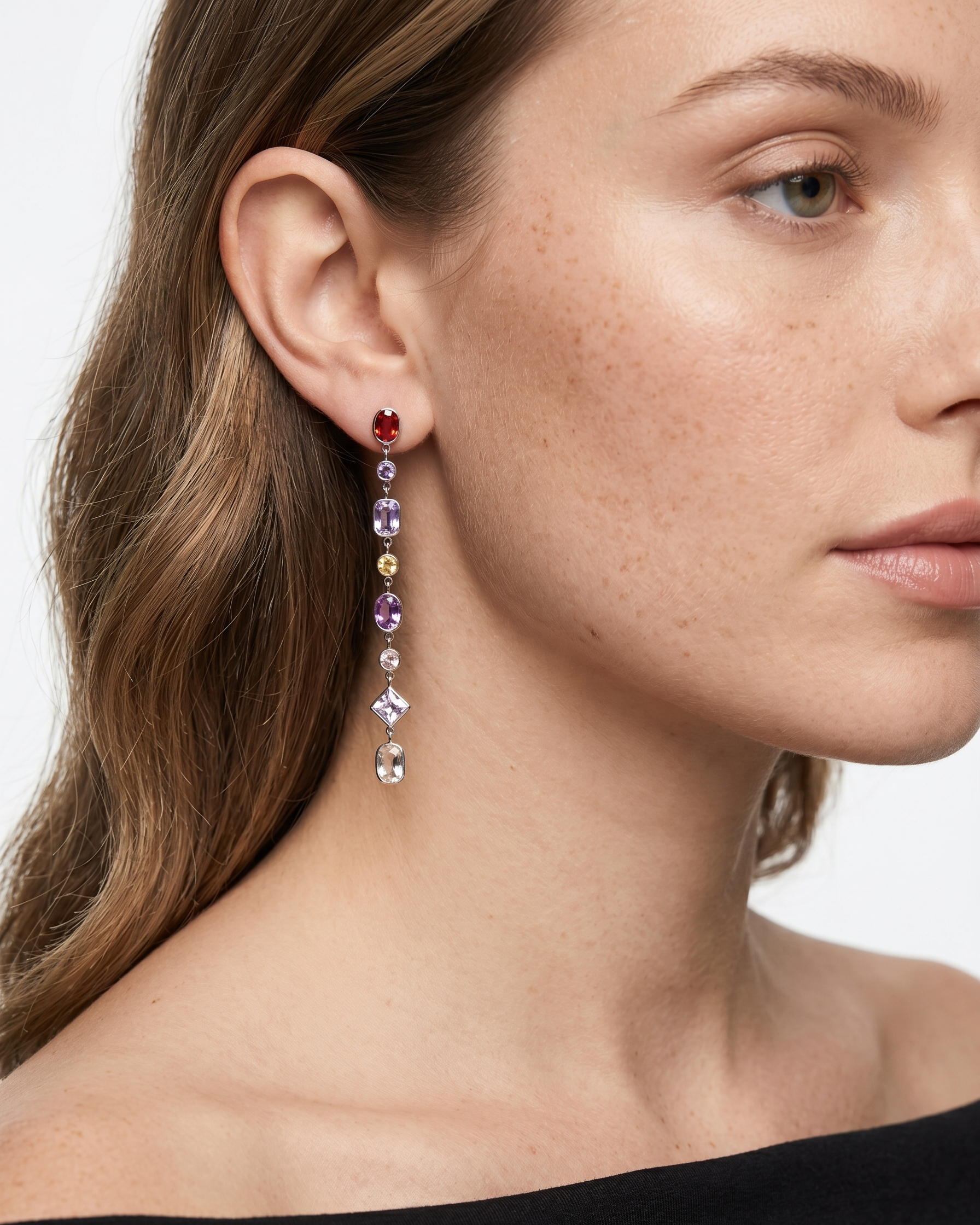 Close-up of a woman wearing colorful earrings with a neutral background
