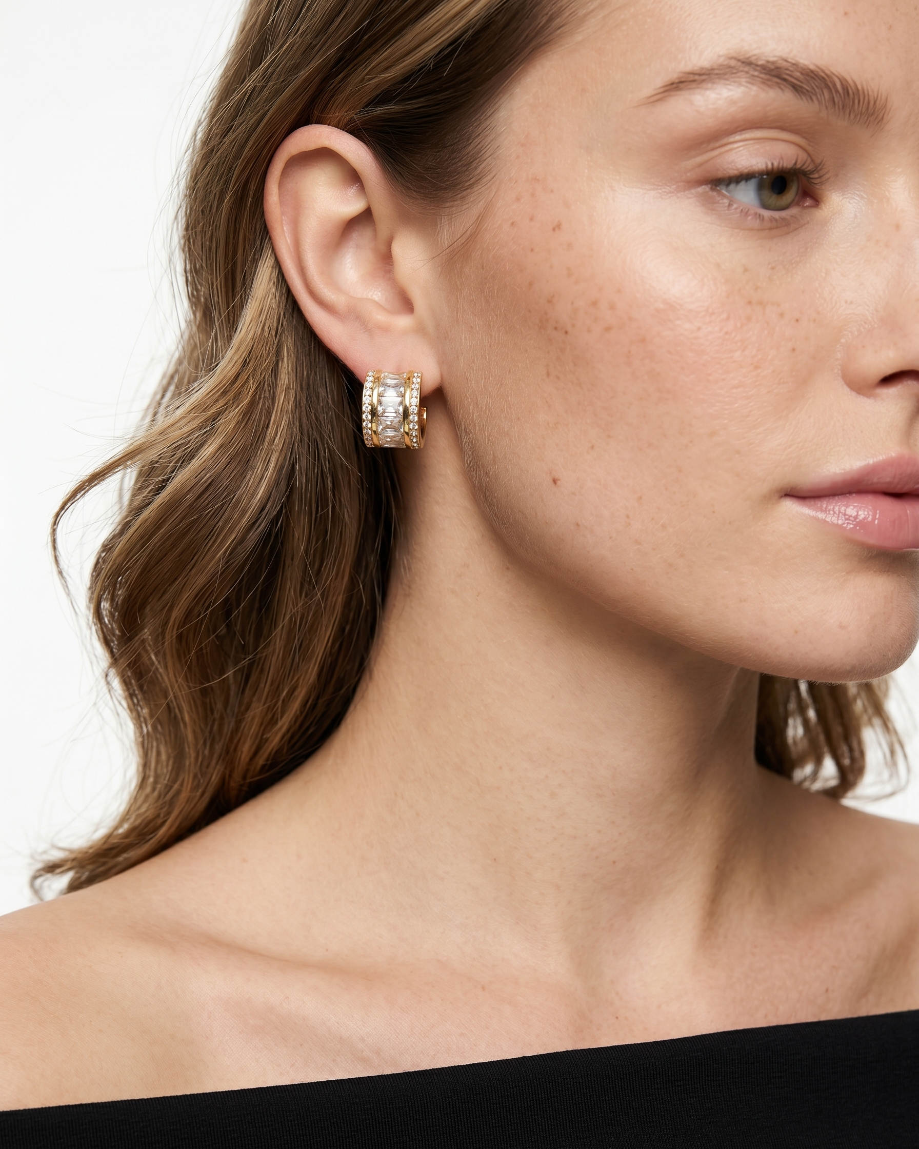 Close-up of a woman wearing gold hoop earrings with a white background
